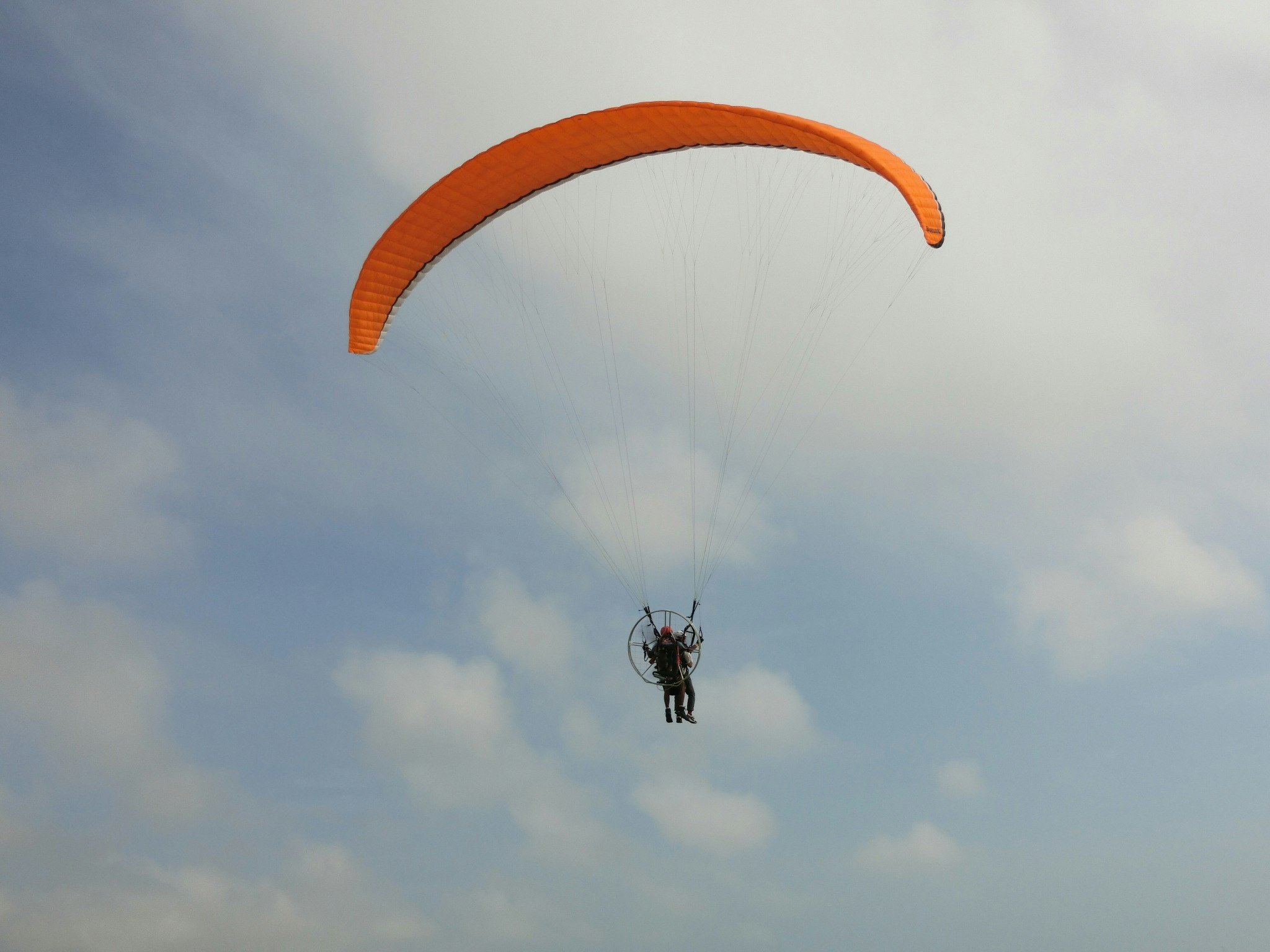 A paraglider flying under a blue sky