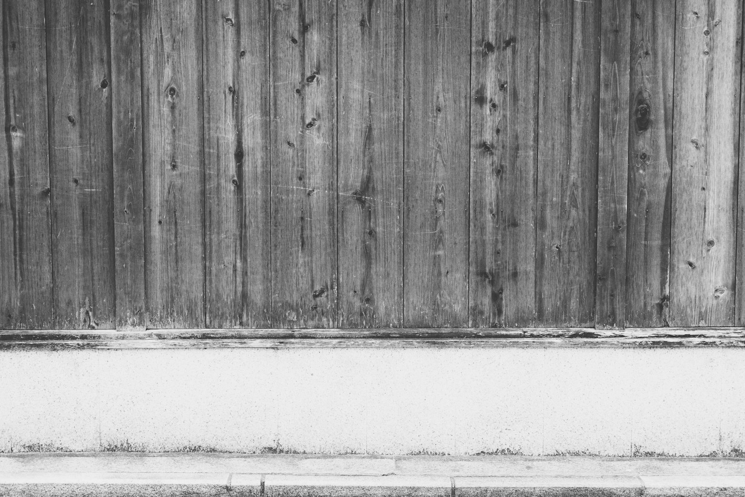 Monochrome image featuring wooden wall texture and white base