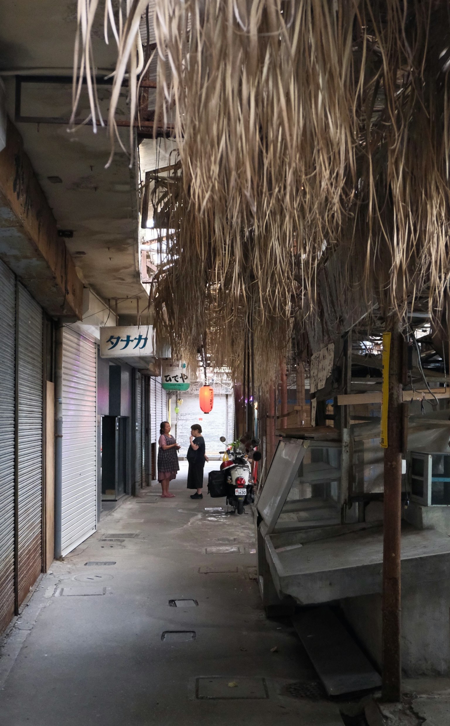 狭い通りに干し草の屋根があり人々が集まっている