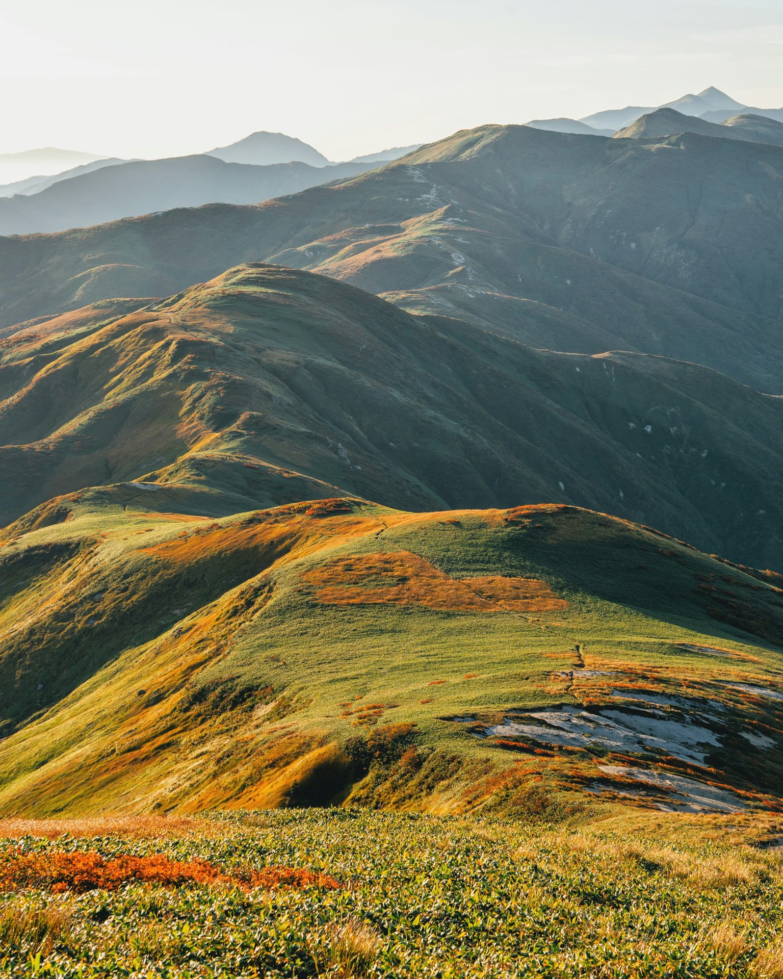 Landschaft mit grünen Hügeln und Bergen bei sanfter Beleuchtung
