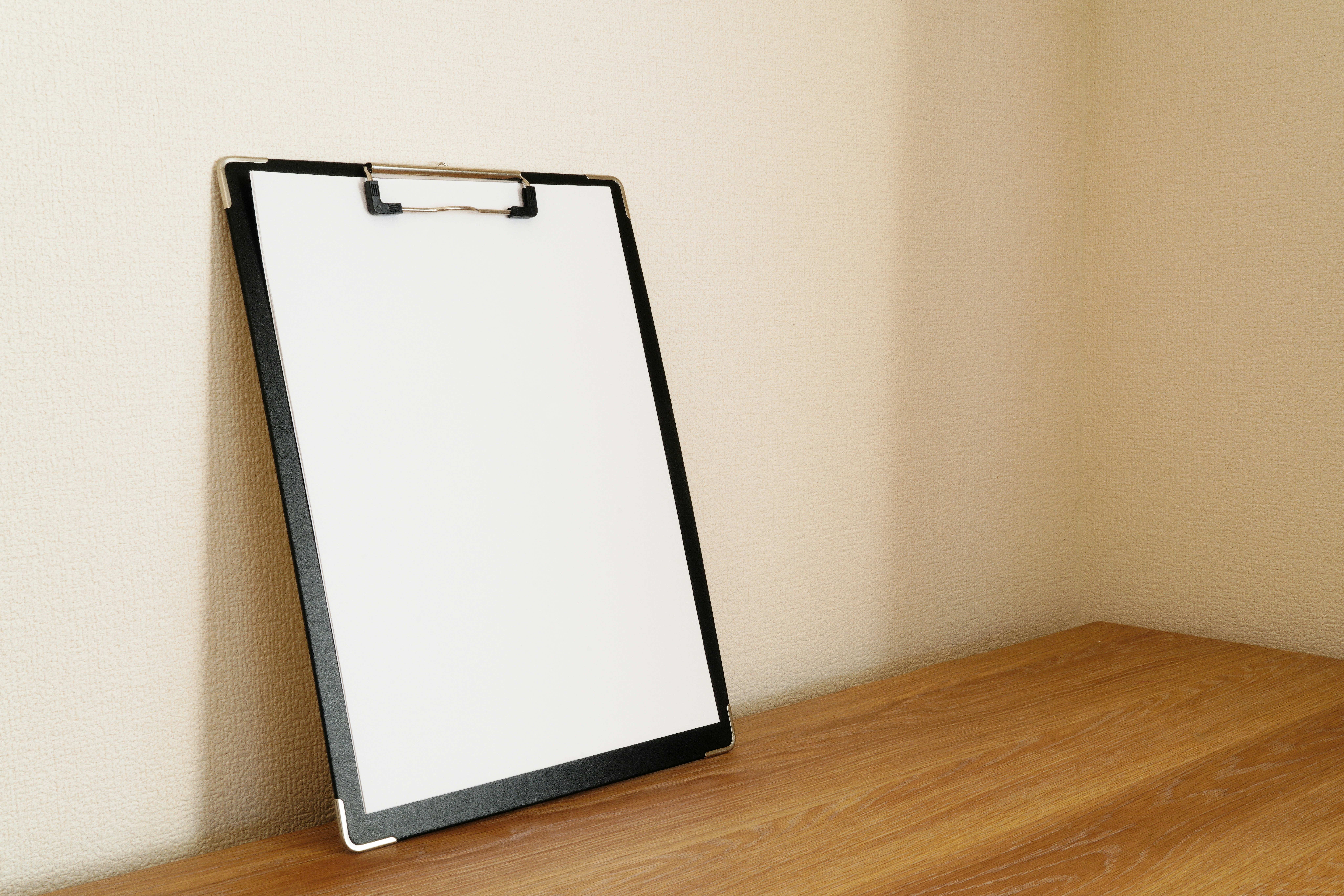 white sheet clipboard on a wooden desk by the wall