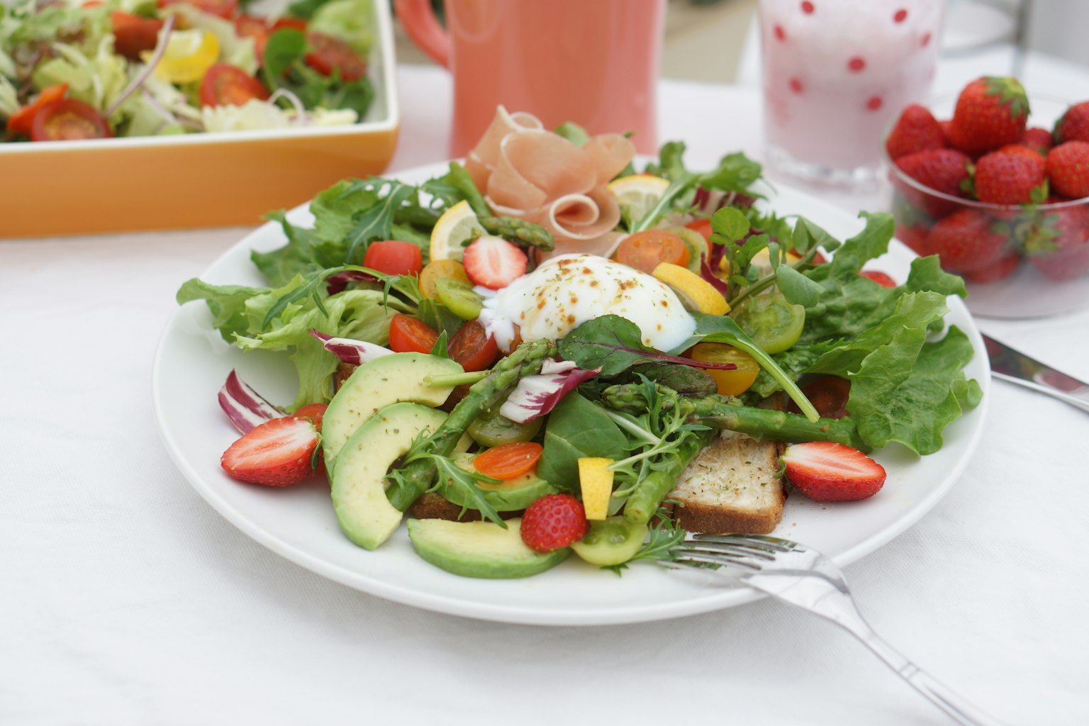Un piatto di insalata con verdure fresche pomodorini avocado e una fetta di pane