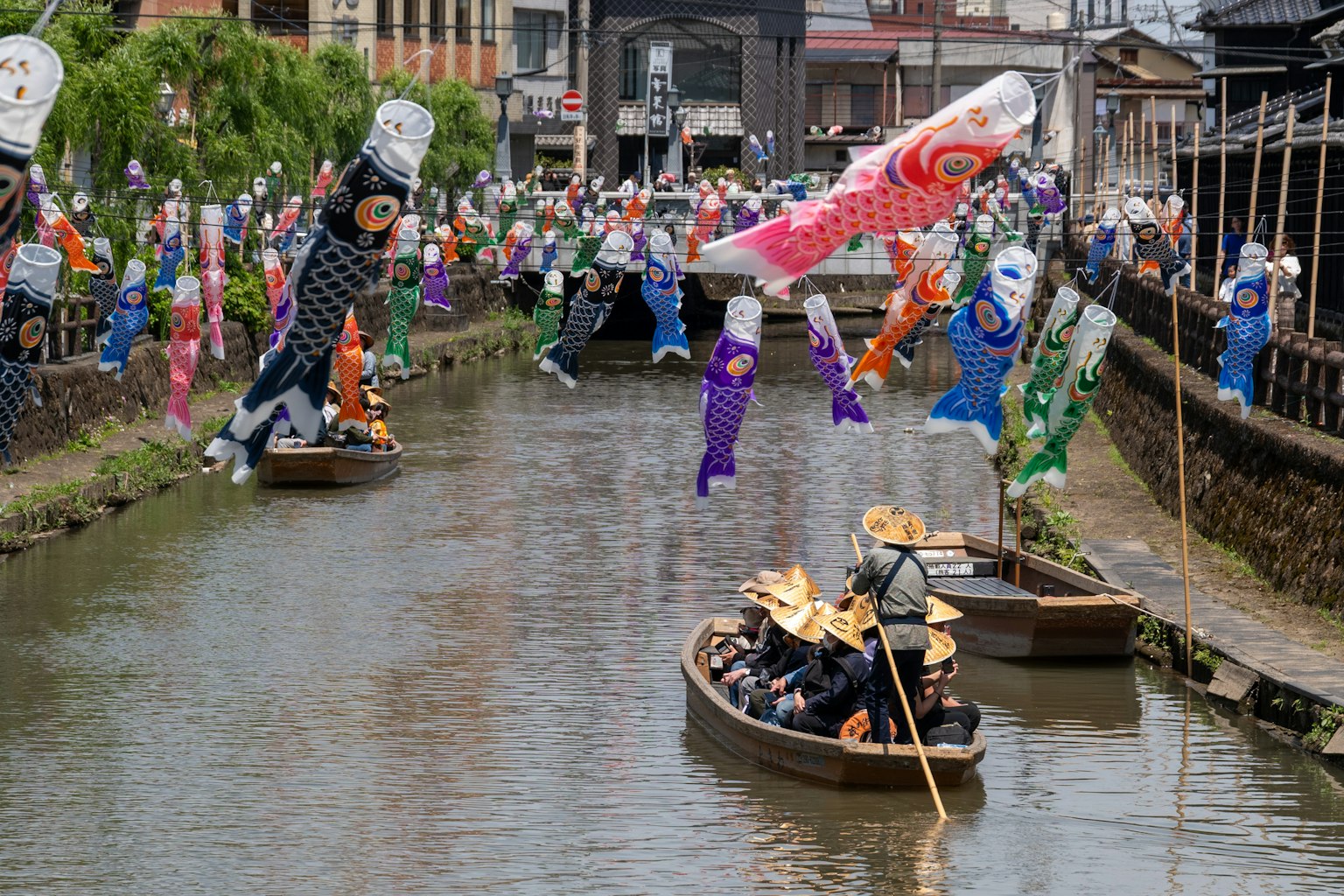 Drapeaux koi nobori colorés flottant au-dessus d'une rivière avec des bateaux traditionnels