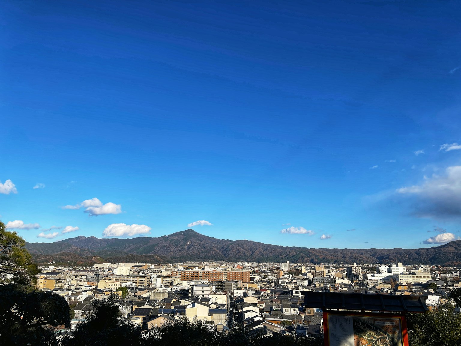 Panoramic view of Kyoto cityscape under blue sky with mountains