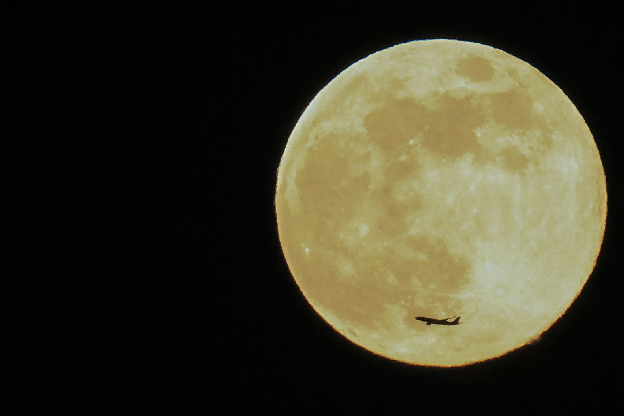 黒い空に浮かぶ月と小さな飛行機雲