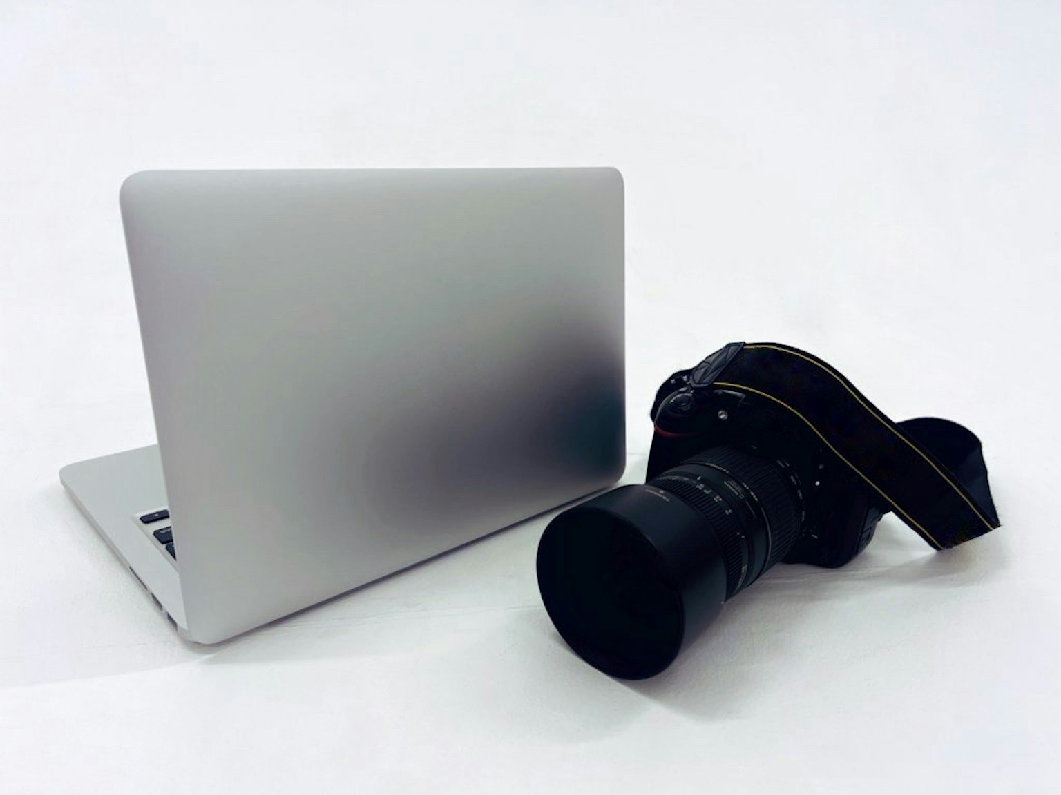 Portátil plateado y cámara colocados uno al lado del otro