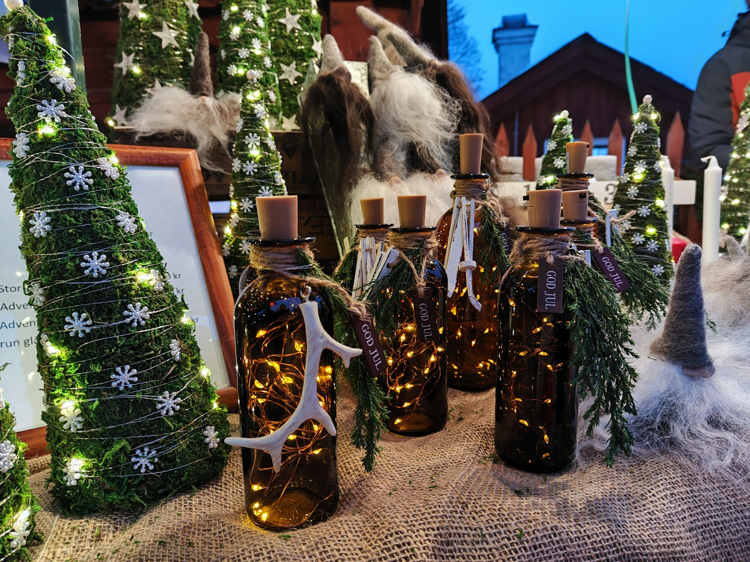 Una esposizione di bottiglie decorate e alberi di Natale con luci