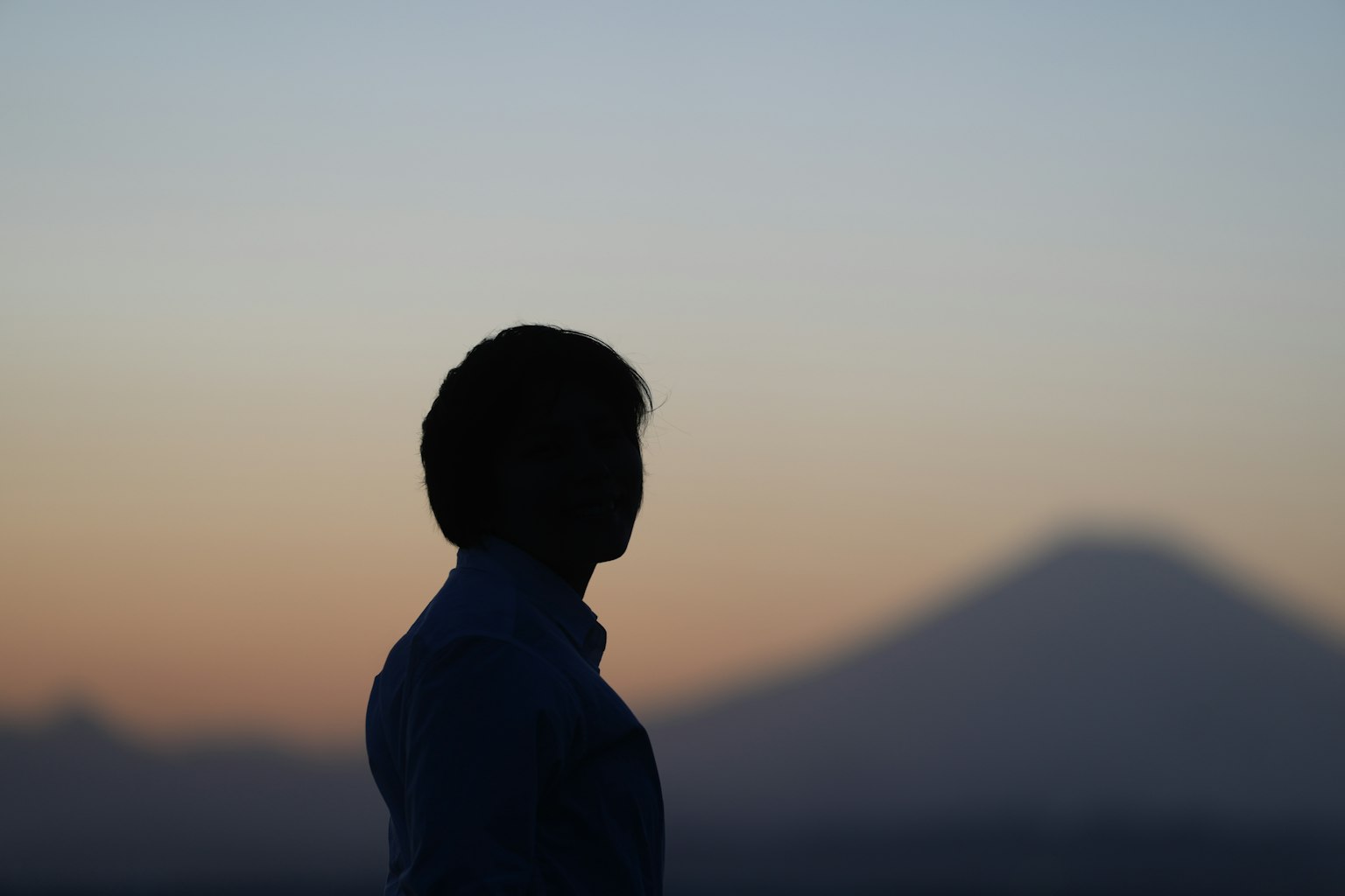 Silhouette eines Mannes vor einem Sonnenuntergang mit Bergen im Hintergrund