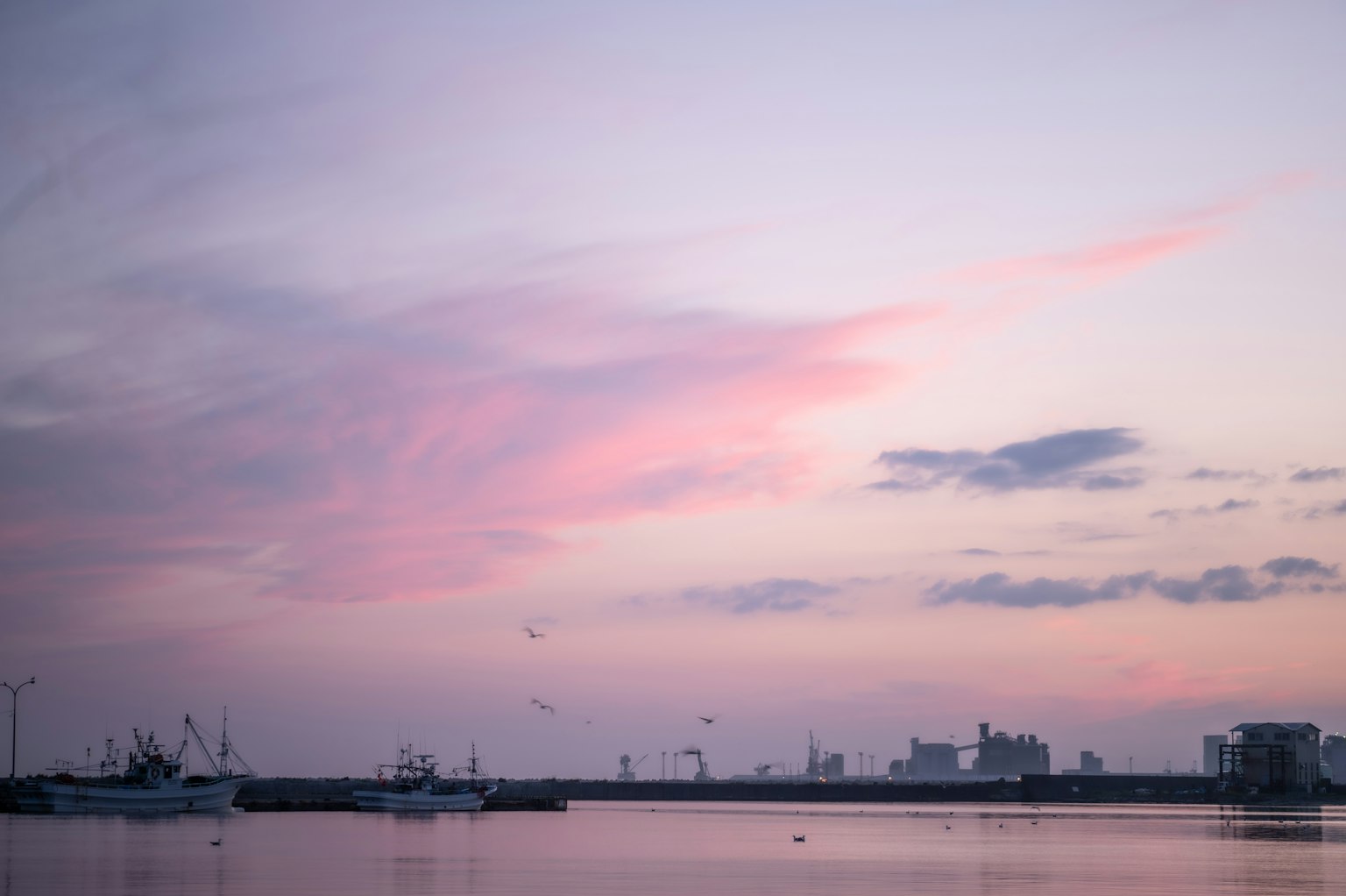 Bateaux de pêche silhouettés contre un coucher de soleil coloré sur la mer calme