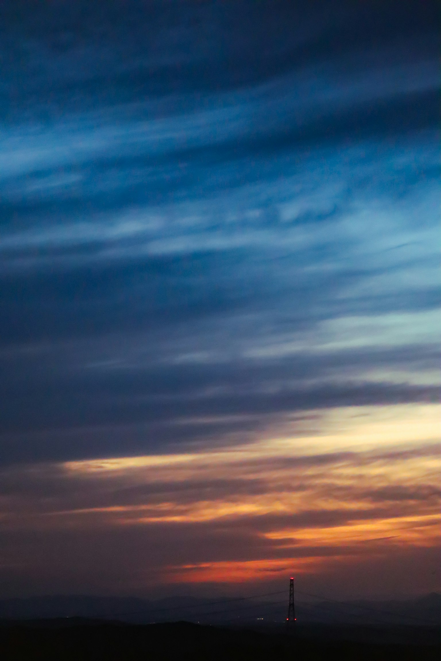 Un magnifique ciel de coucher de soleil avec des dégradés de bleu et d'orange silhouettant une tour lointaine à l'horizon