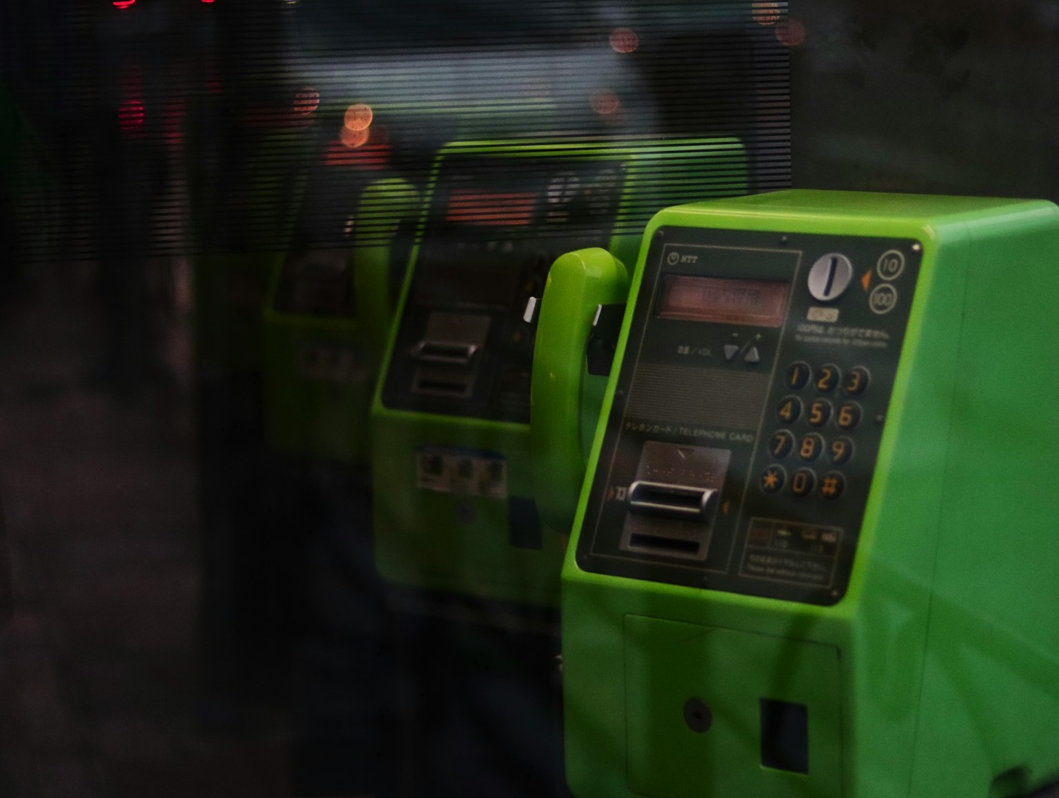 Rangée de téléphones publics verts avec claviers visibles
