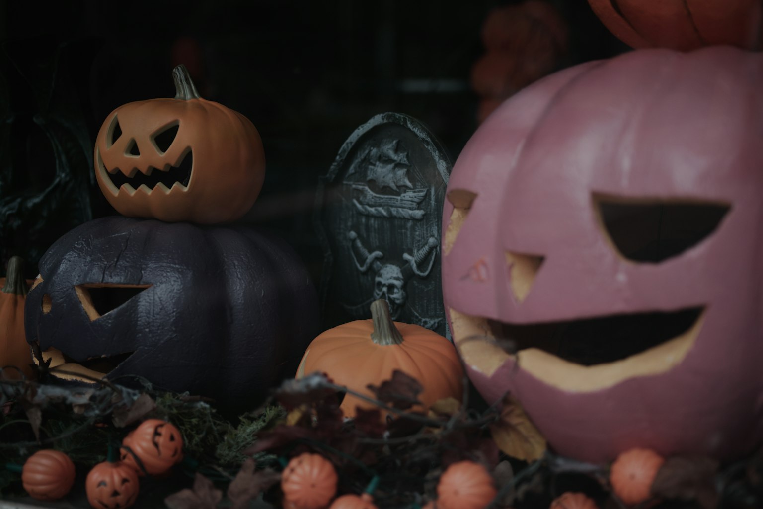 Eine Szene mit Halloween-Kürbissen mit geschnitzten Gesichtern, darunter ein lila Kürbis und ein orangefarbener Kürbis