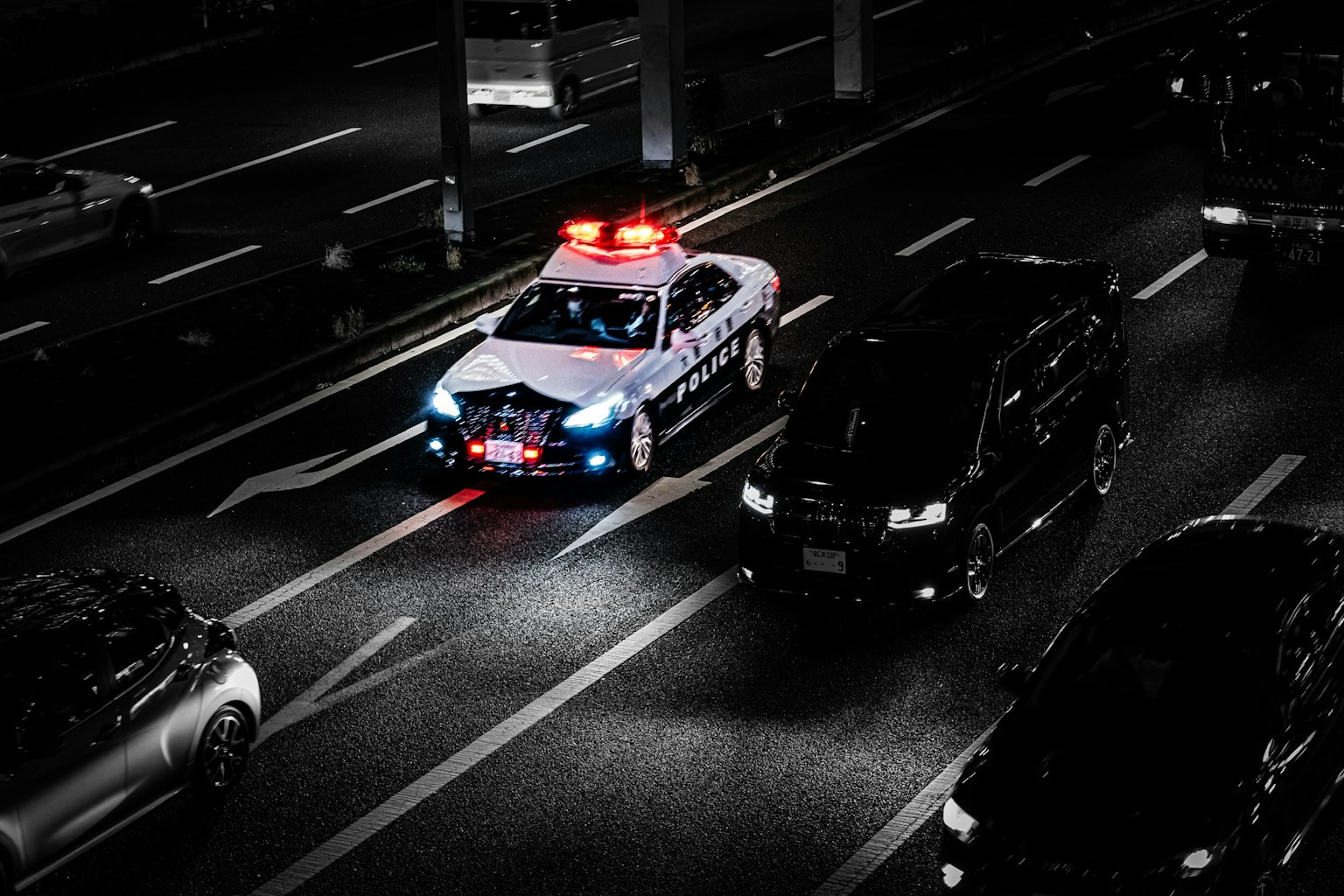 一辆闪烁着红色和蓝色灯光的警车在夜间道路上穿行