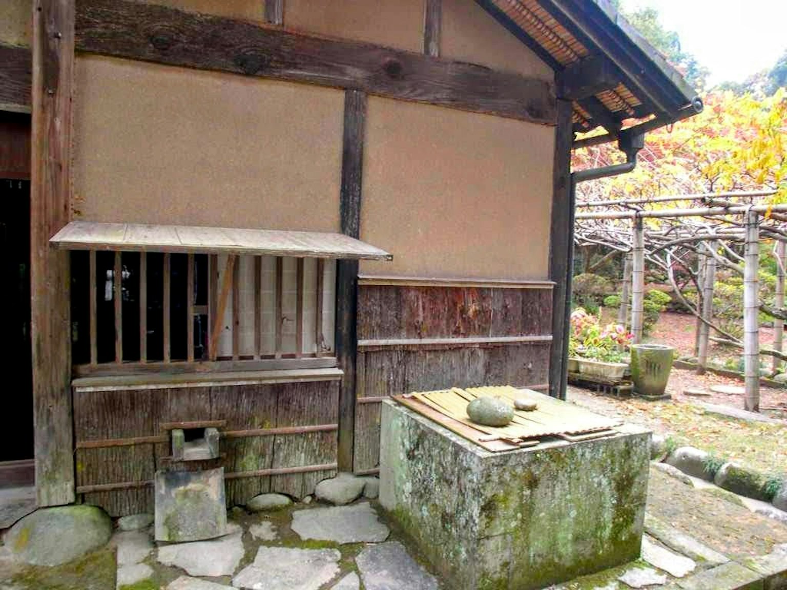 Extérieur d'une maison japonaise traditionnelle avec structure en bois et en terre plan de travail en pierre et vue sur le jardin