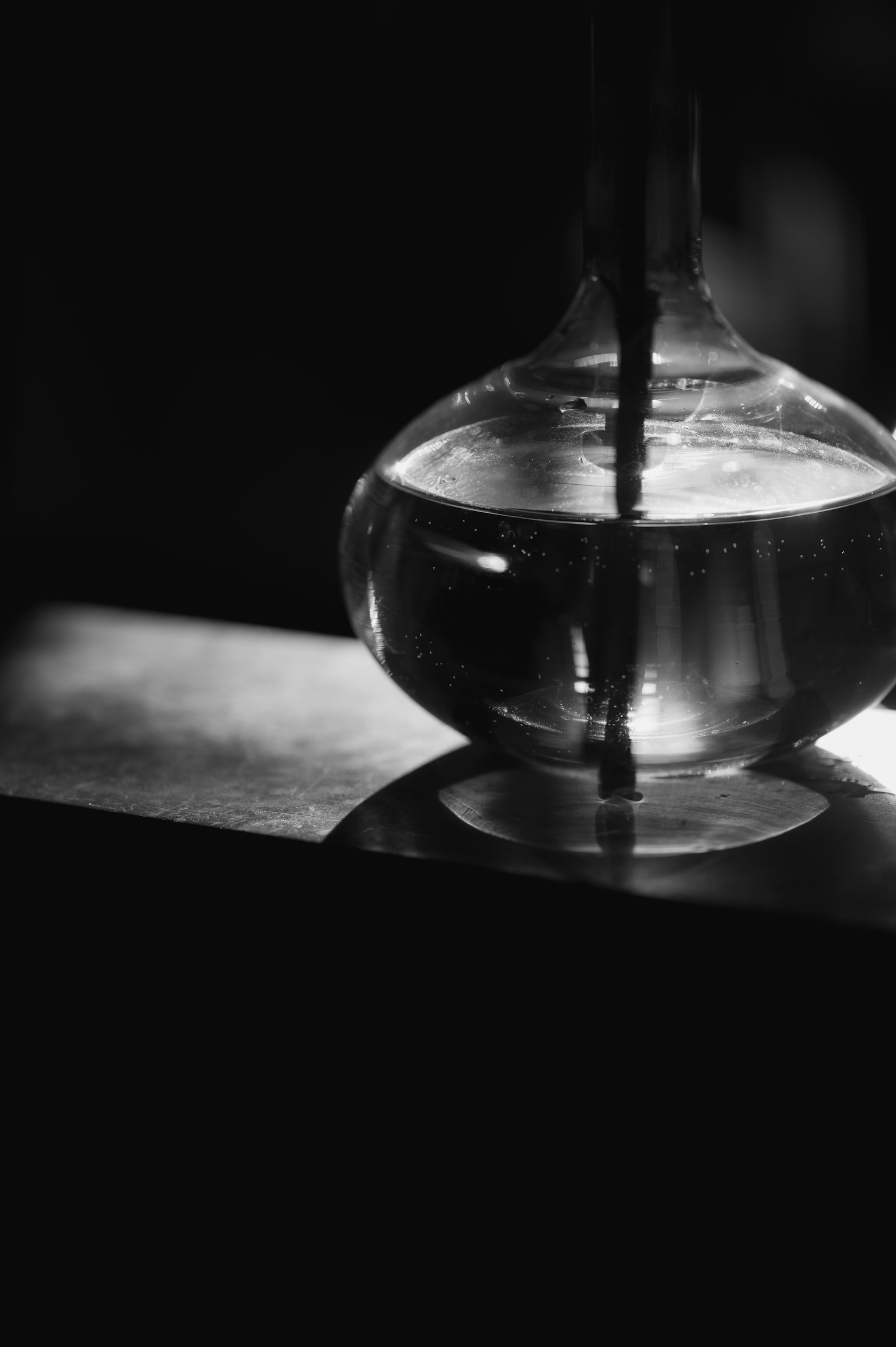 A transparent glass bottle filled with water in a dimly lit setting