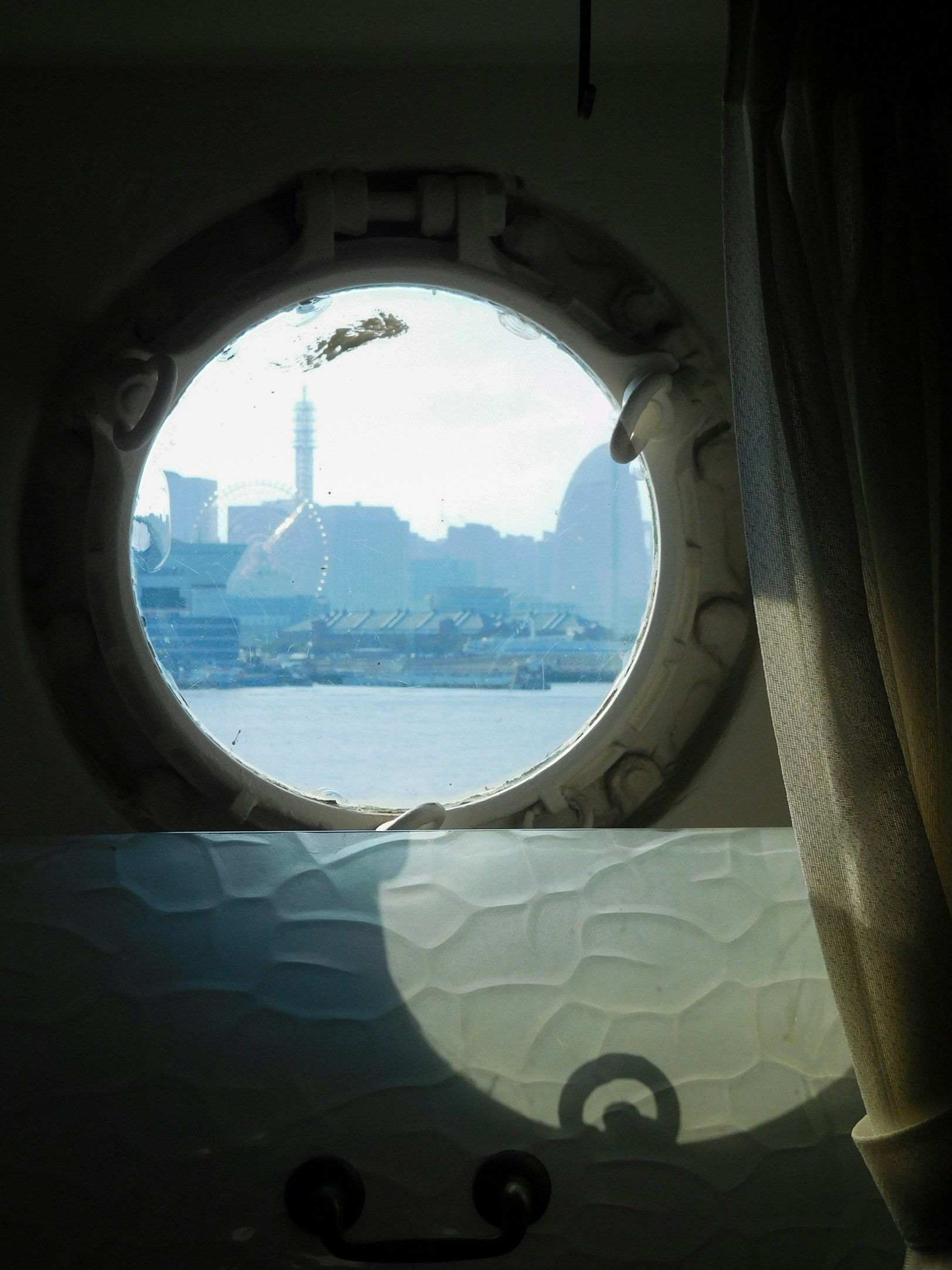 窓の丸窓から見える海と港の景色
