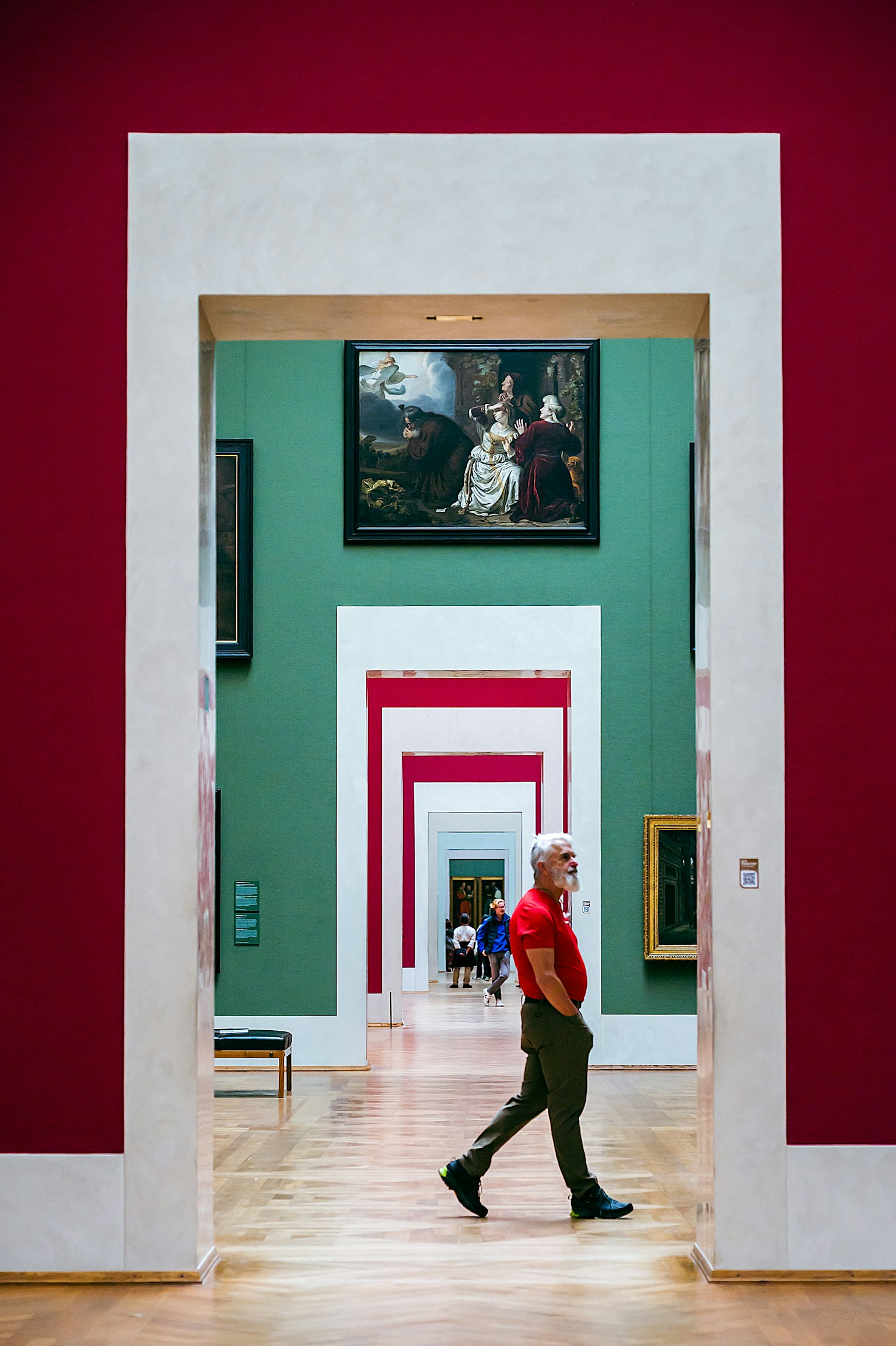 Ein Mann, der durch eine Kunstgalerie mit roten und grünen Wänden geht