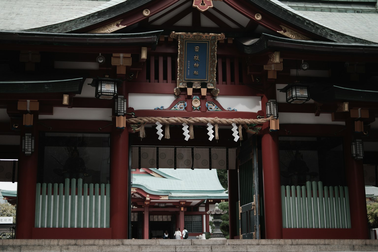 붉은 기둥과 초록색 격자 창이 있는 신사의 입구