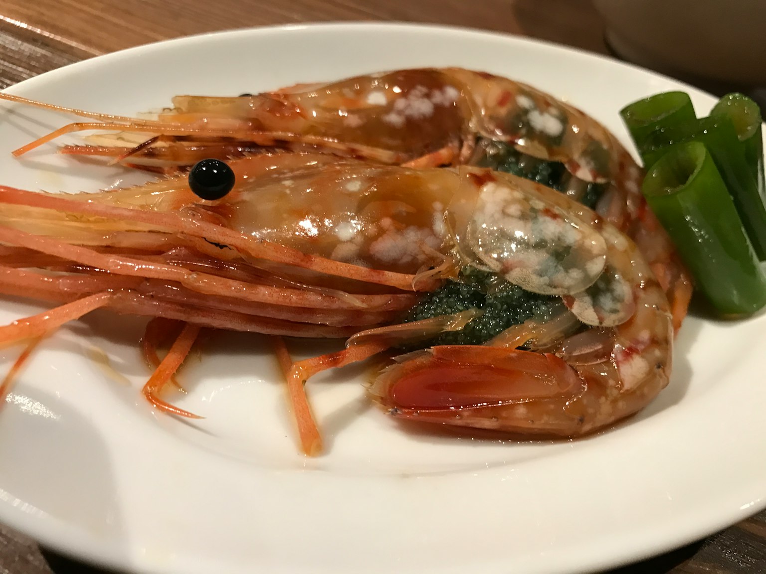 Gamberi freschi su un piatto con verdure verdi