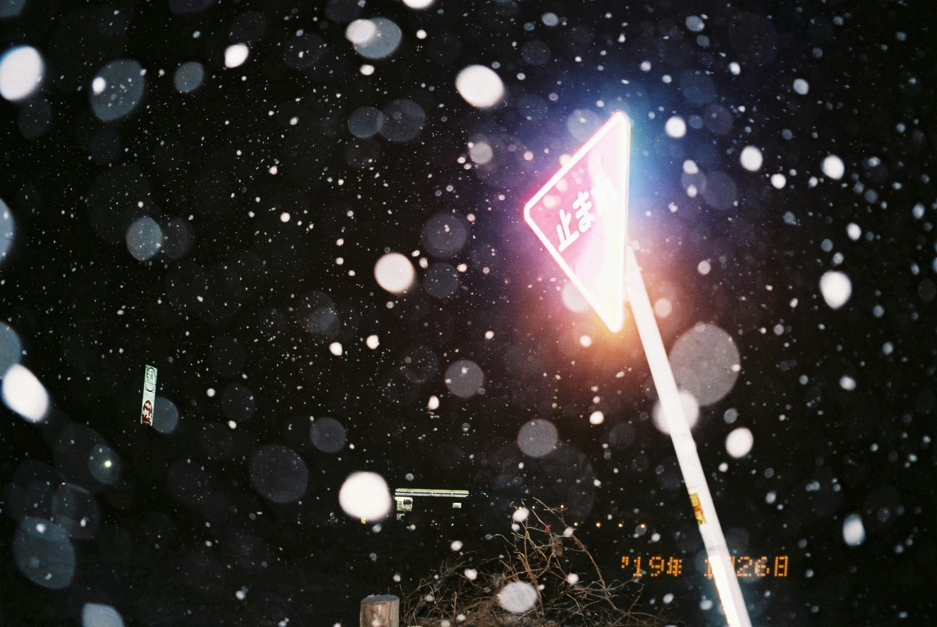 夜晚街角发光招牌与飘落的雪粒光点