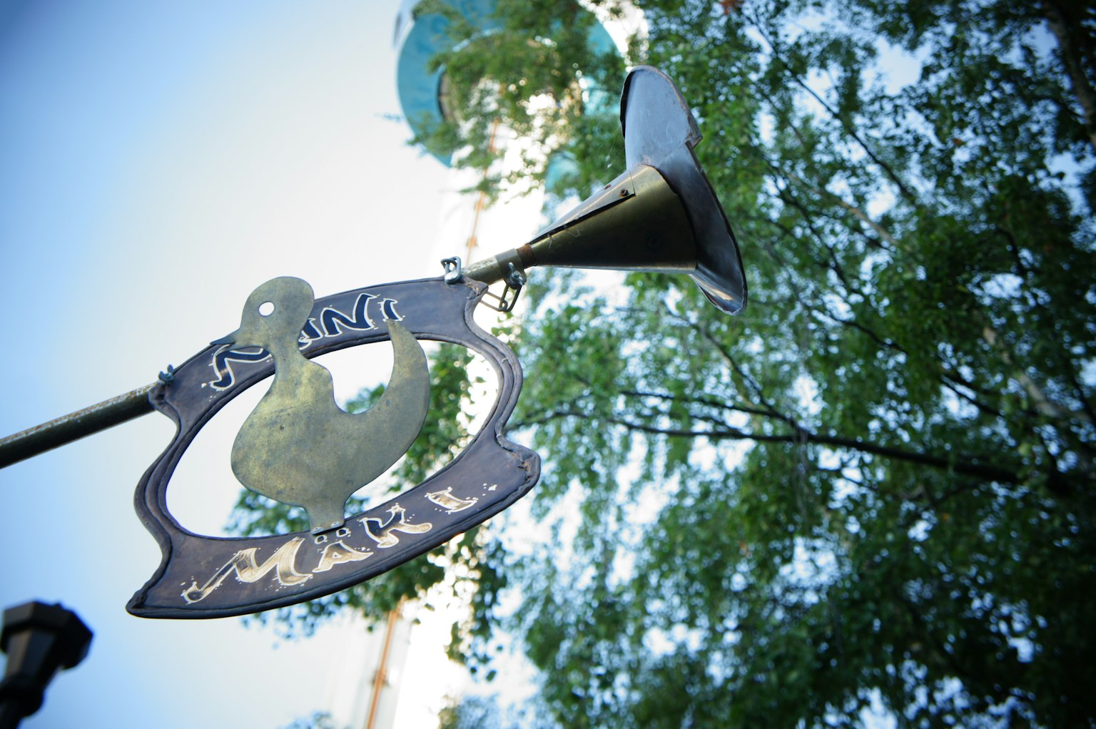 Sign featuring a duck design against a blue sky