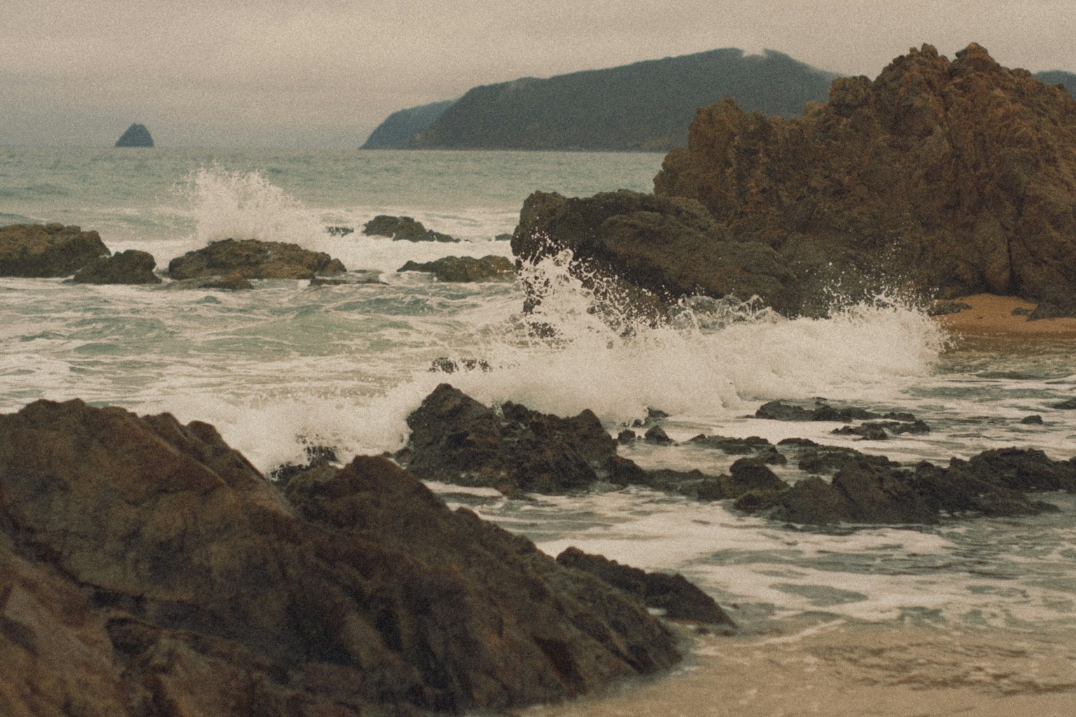 海岸風景，岩石和波浪，遠處有山