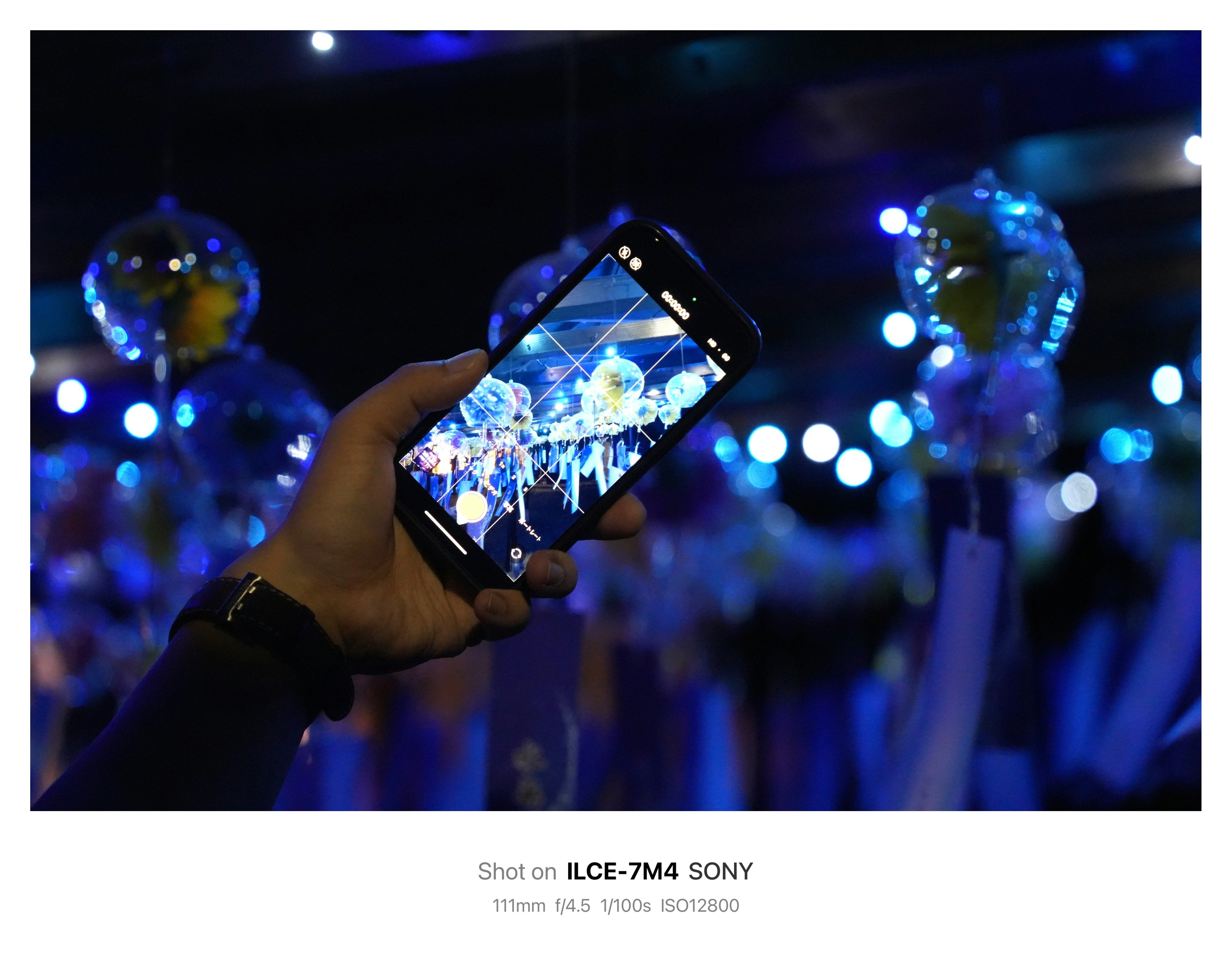 夜のイルミネーションをスマホで撮影する手元