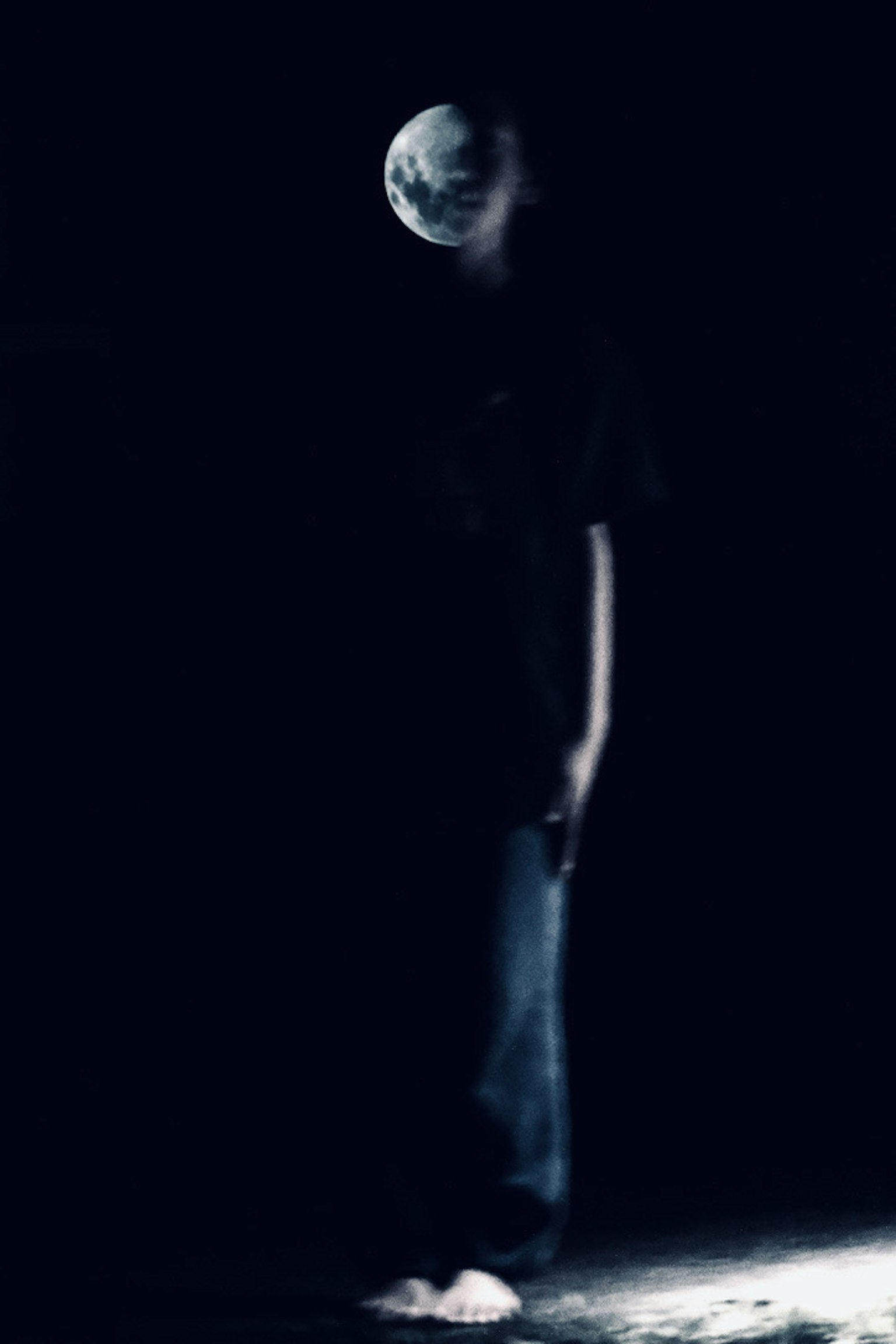 A silhouette standing in darkness with the Earth floating above its head