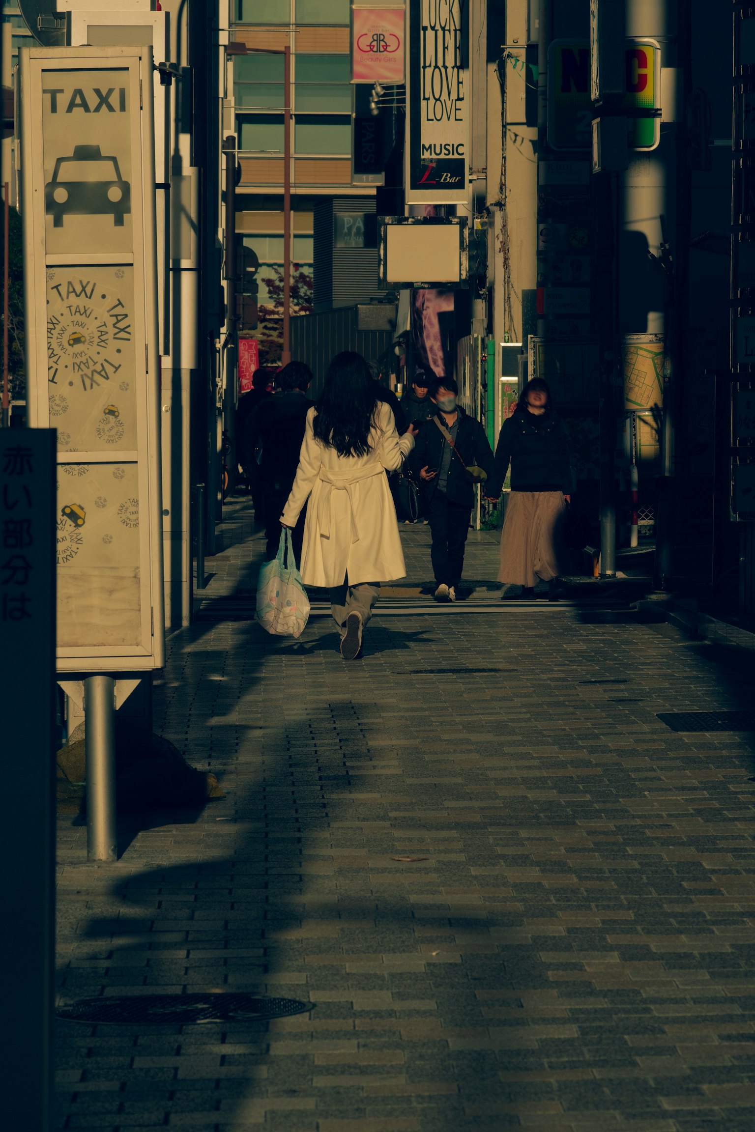 여성이 저녁에 도시 거리에서 흰색 코트를 입고 걷고 있음