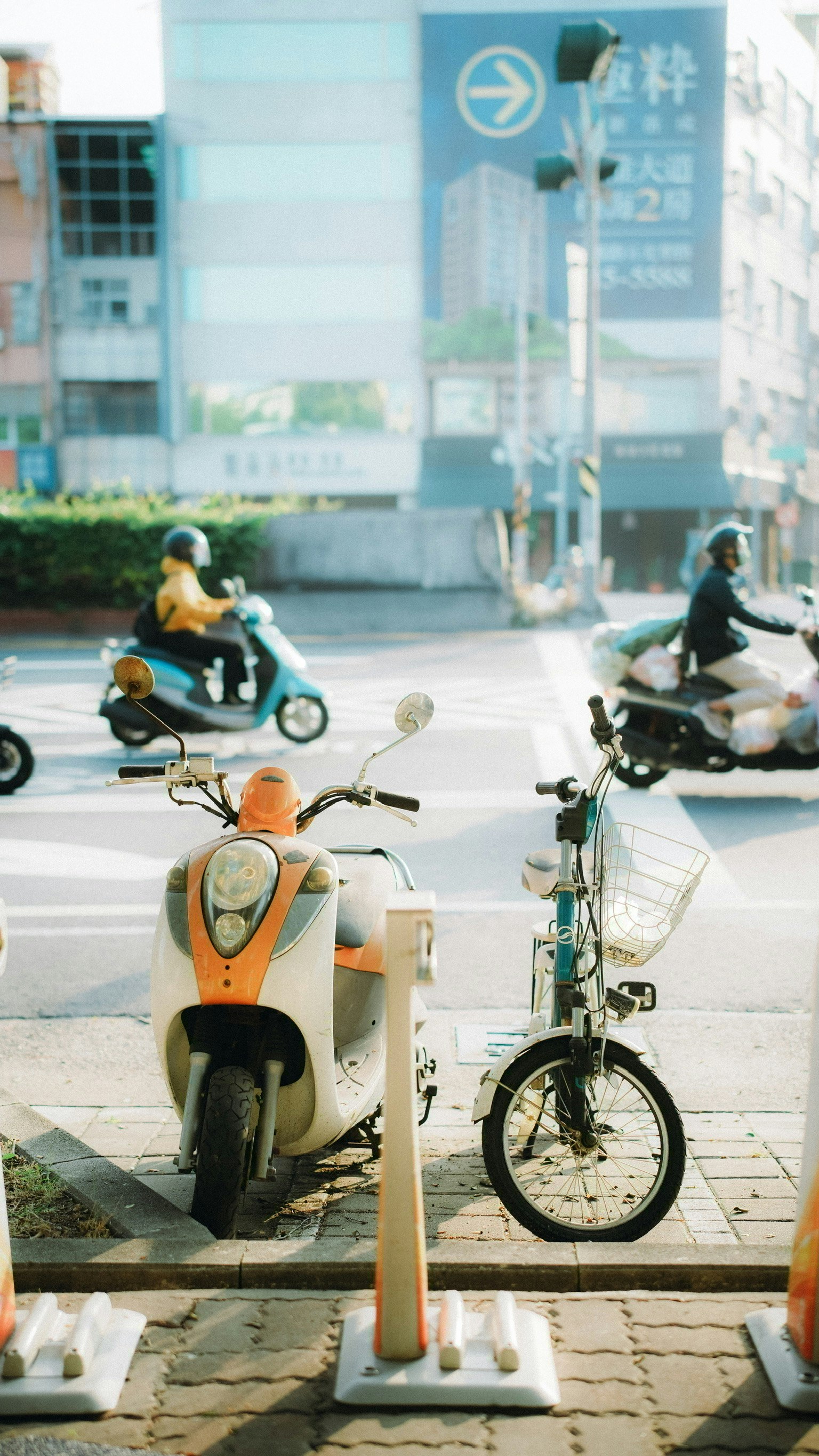 街道場景，在十字路口有一輛橙色滑板車和一輛自行車