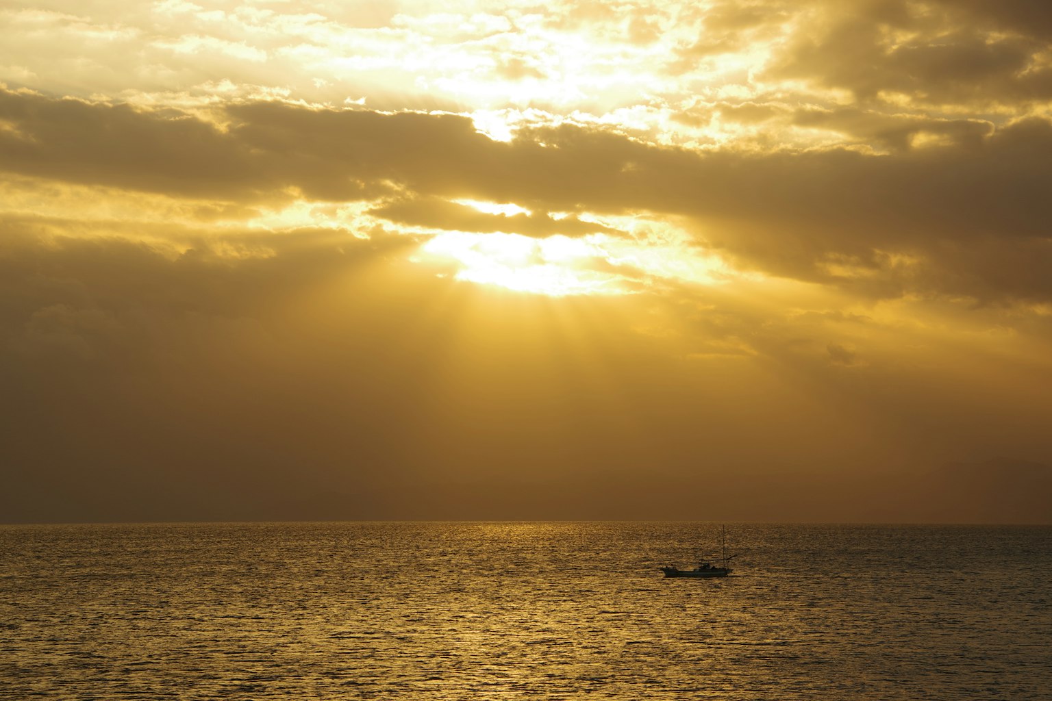 Un petit bateau sur la mer illuminé par la lumière dorée du soleil