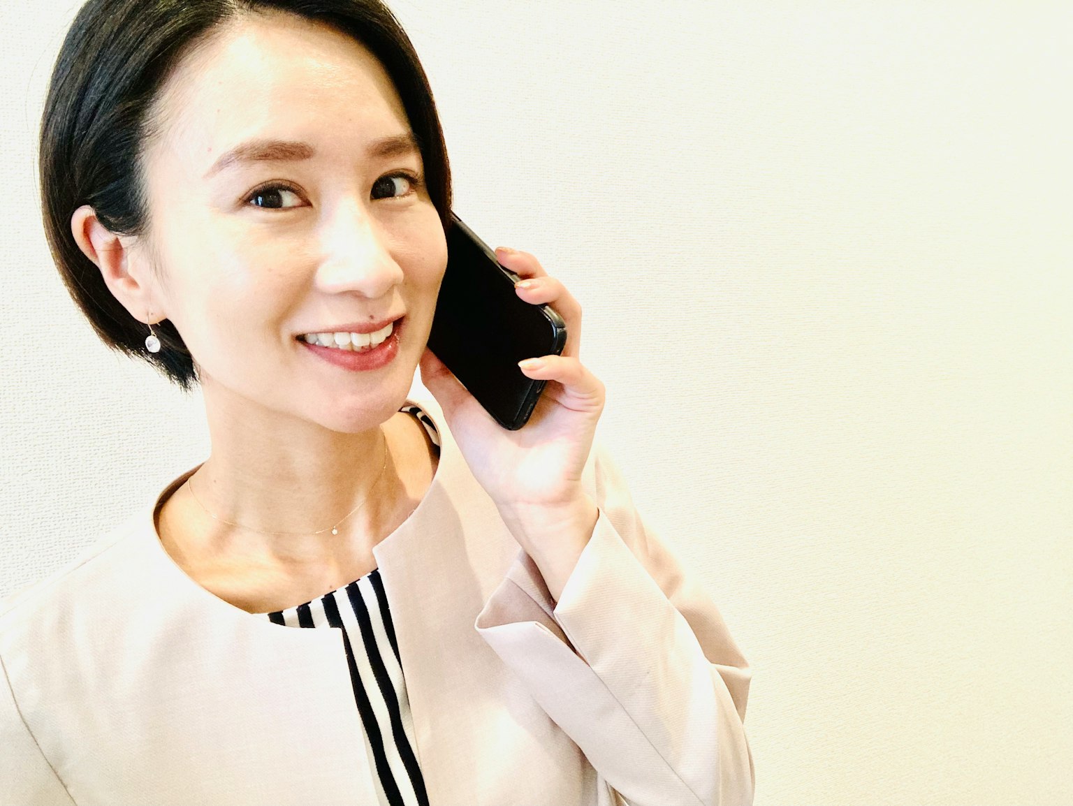 在白色背景前微笑的女性正在打电话