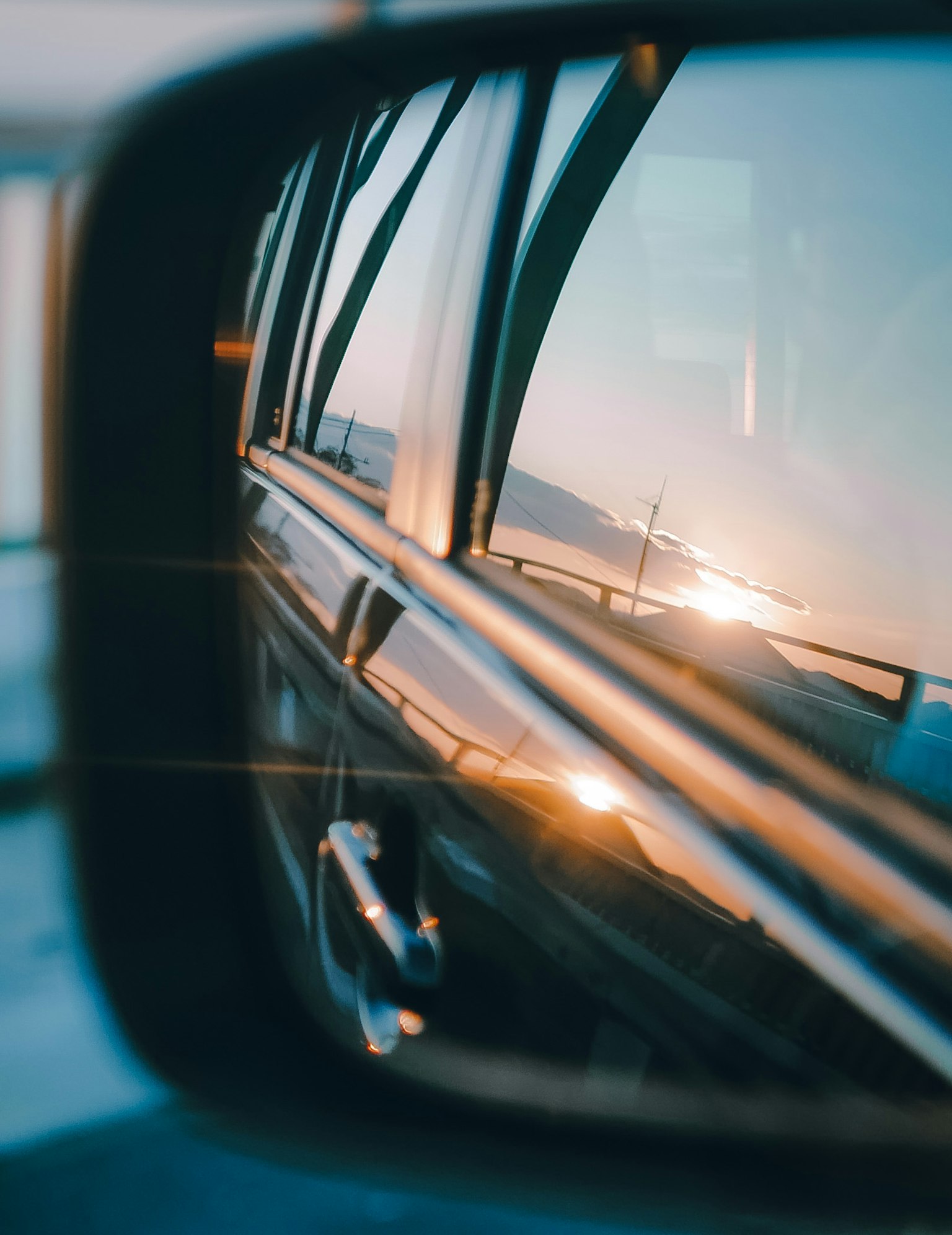 Riflessione del tramonto e dell'oceano in uno specchietto retrovisore di auto