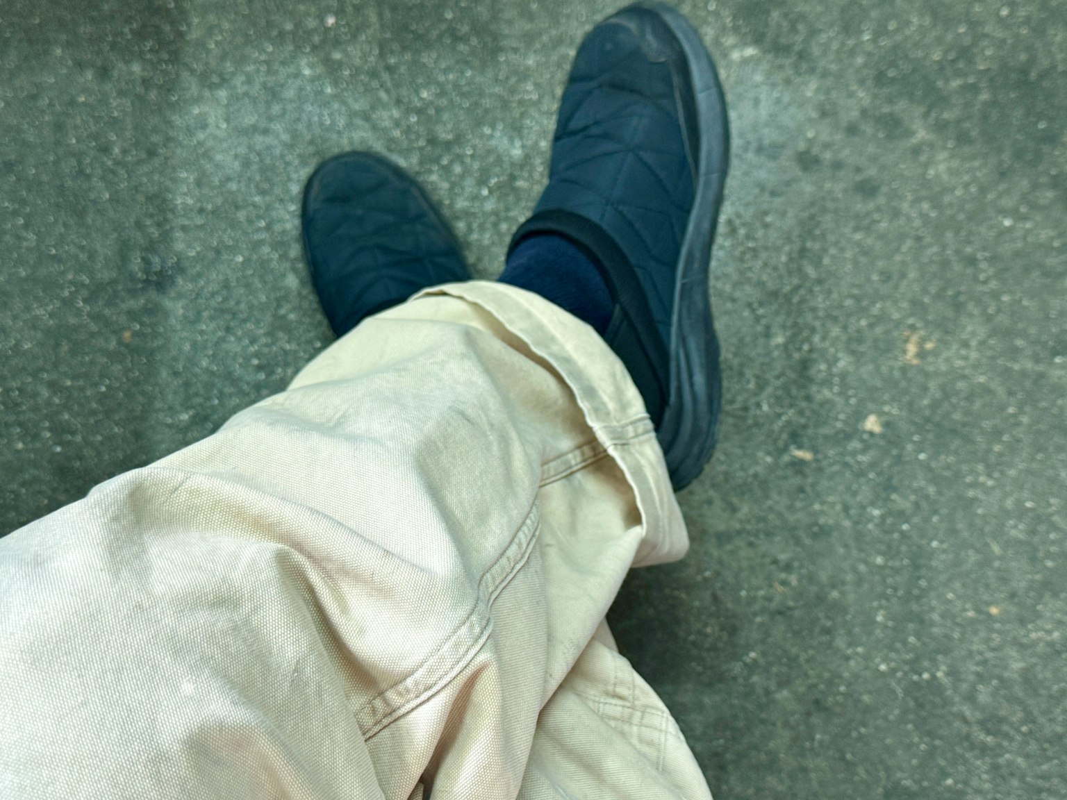 Vista casual dei piedi in sneakers scure e pantaloni chiari