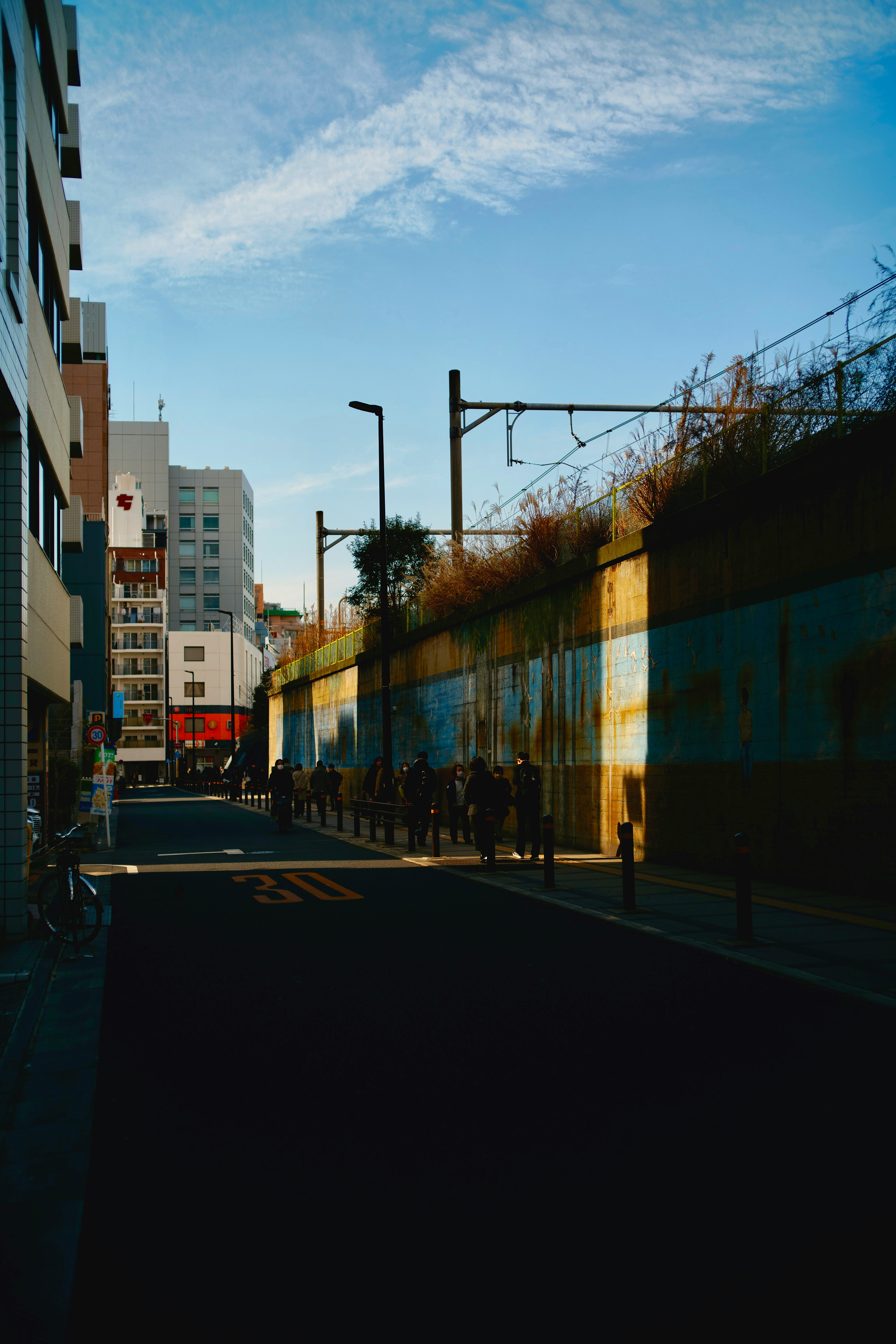 高い壁と街灯が続く都市の路地の夕方風景