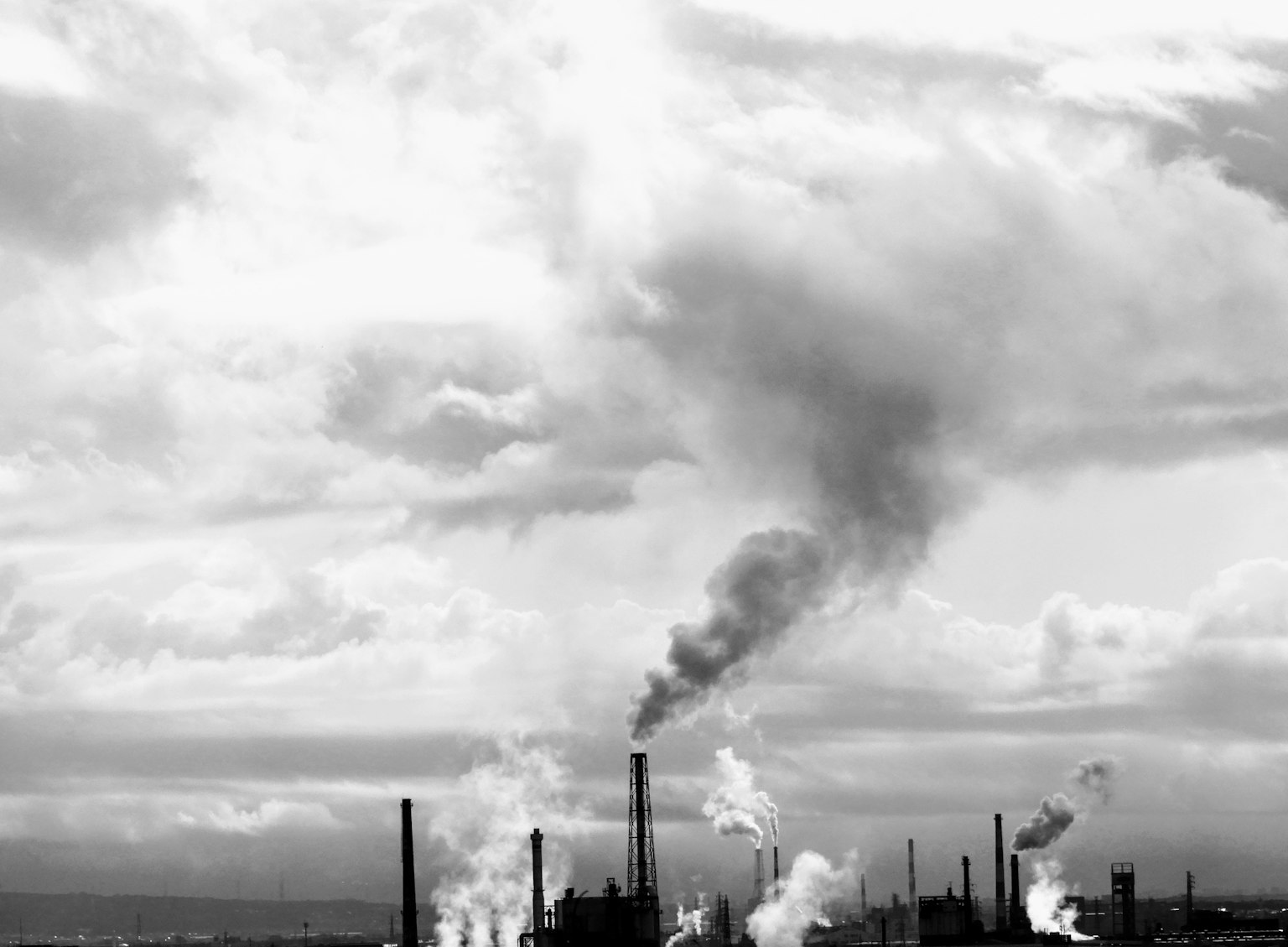 Factory smokestacks emitting smoke against a cloudy sky
