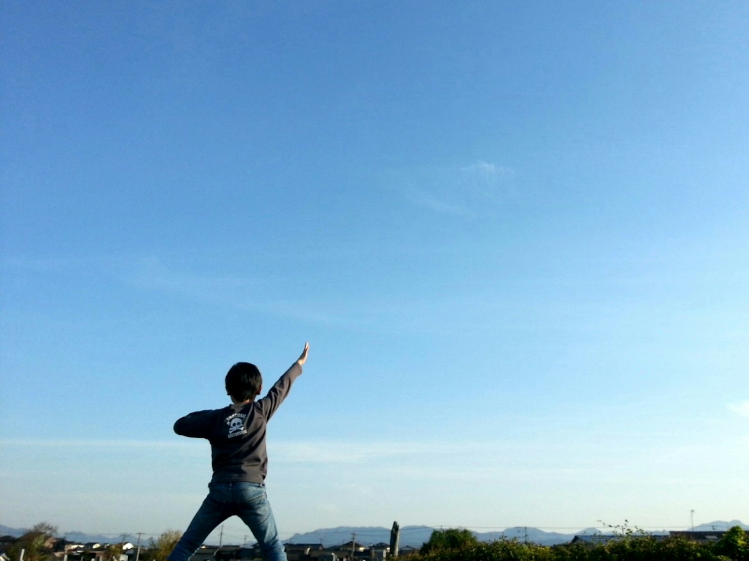 Silhouette d'un enfant posant sous un ciel bleu