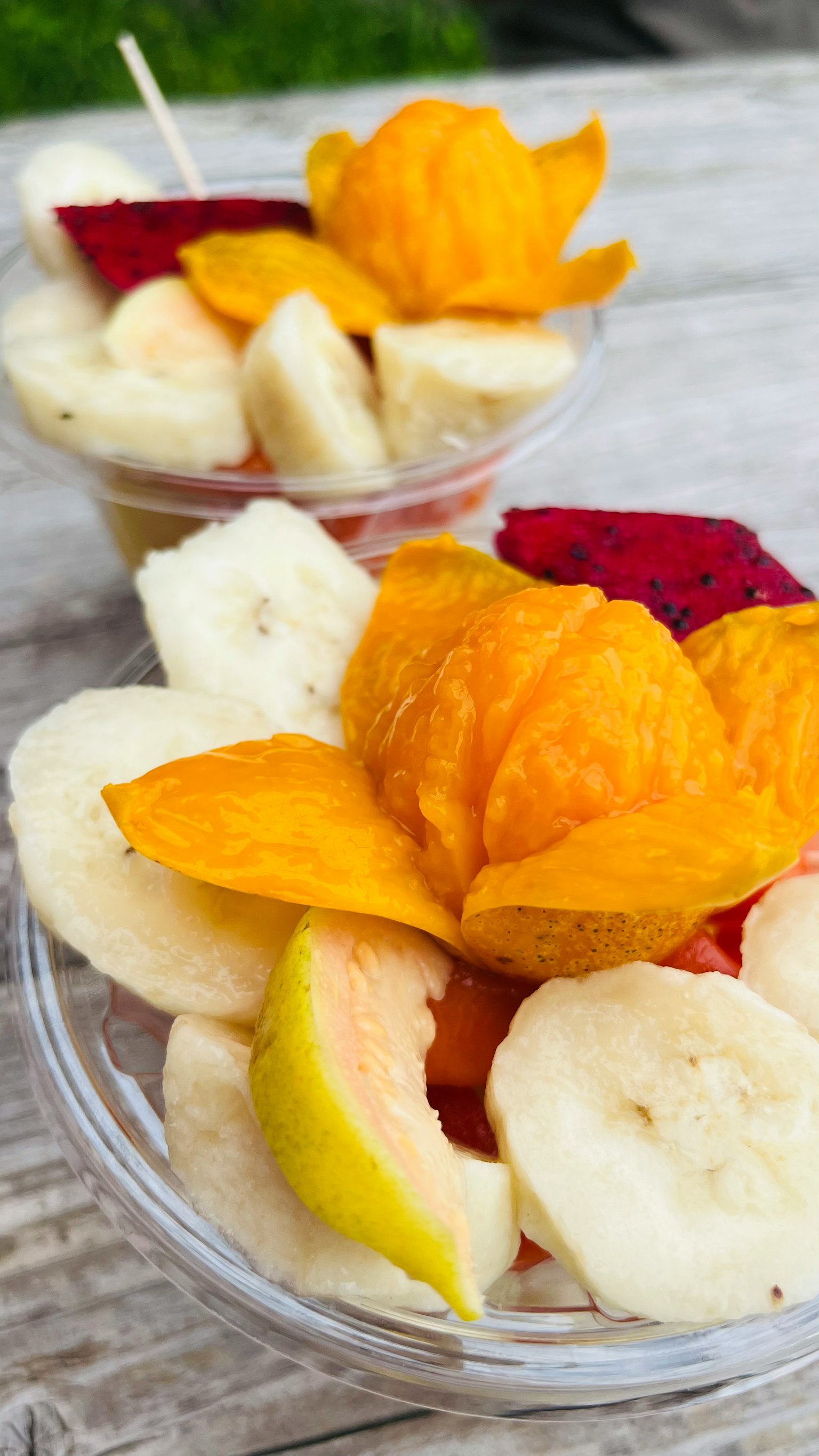 Mangkuk buah dengan pisang, pepaya, buah naga, dan dekorasi bunga buah kering