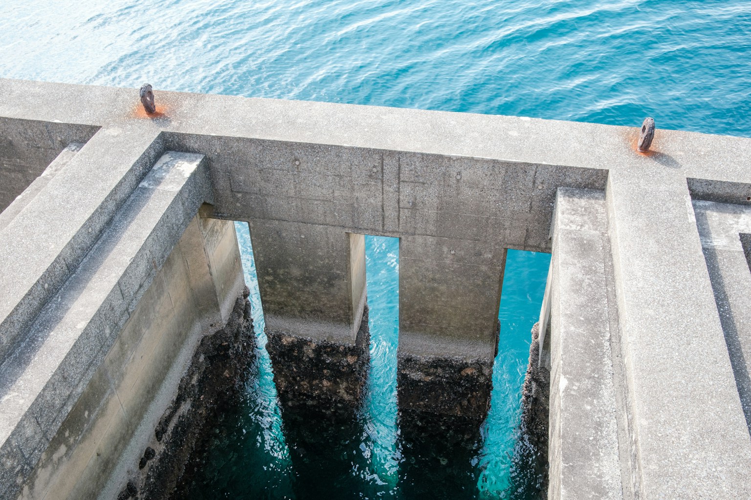 Quai en béton avec supports visibles immergés dans une eau claire