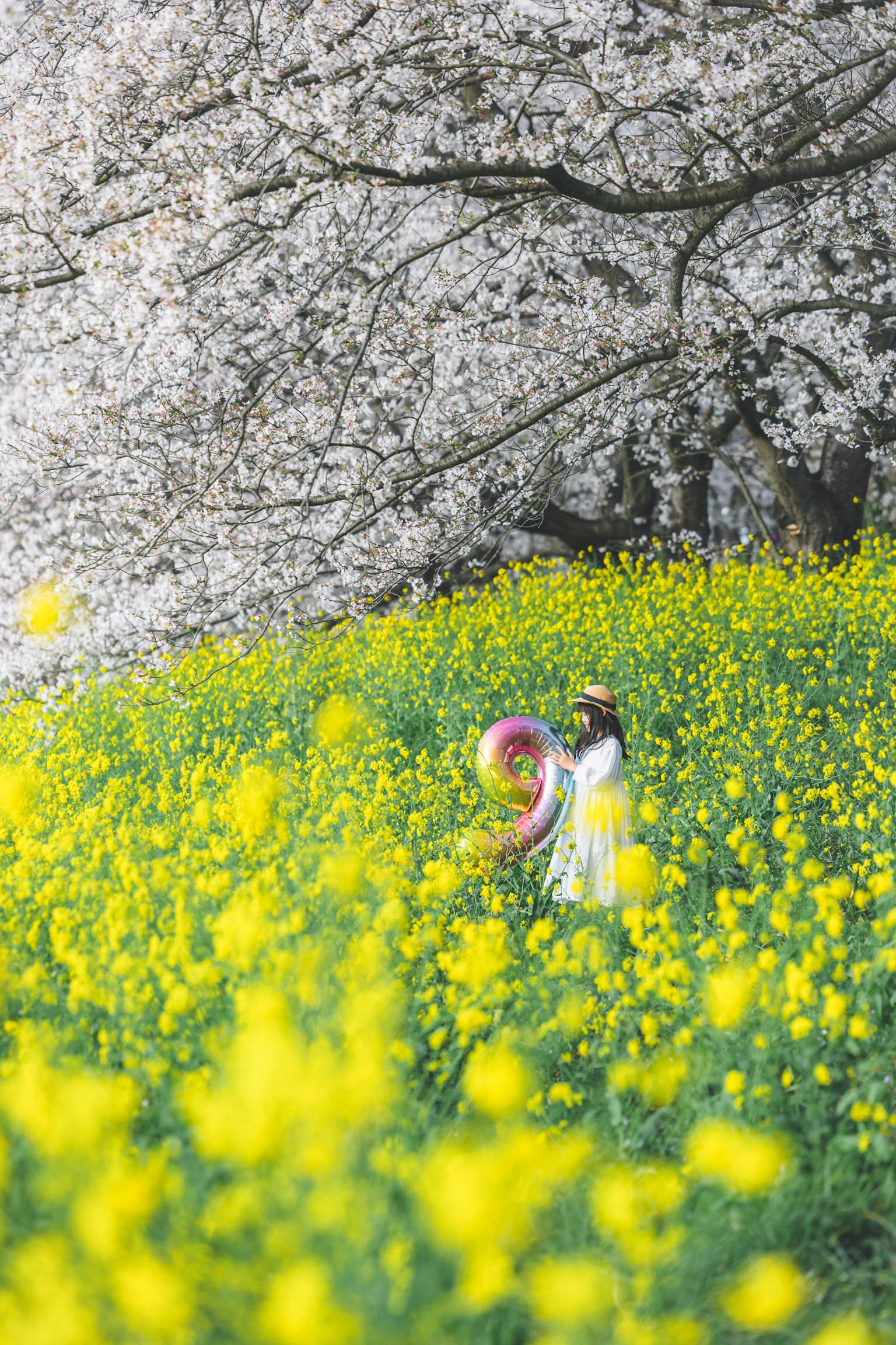 Une femme en robe blanche jouant dans un champ de fleurs jaunes