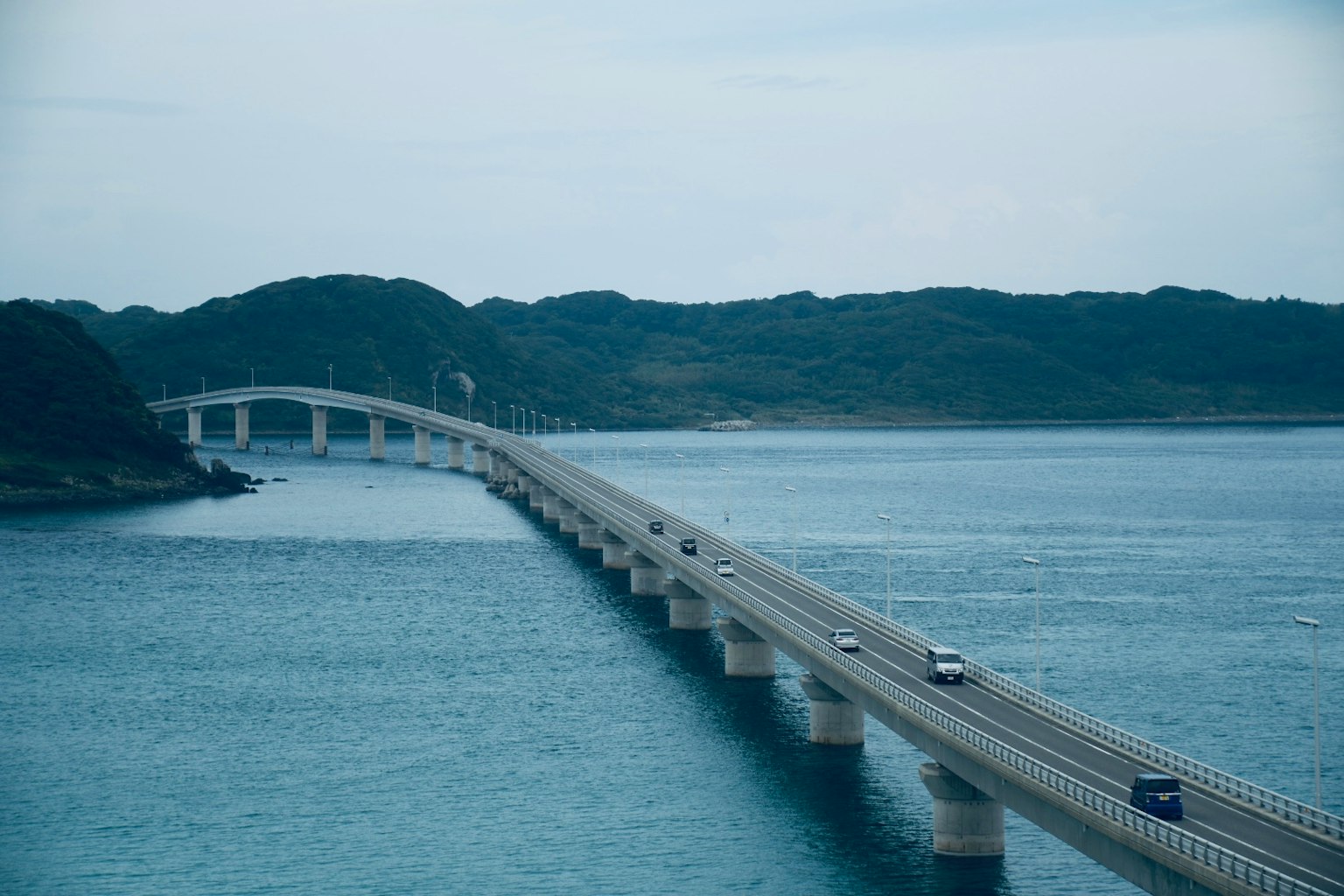Pont sur l'eau bleue avec des collines vertes en arrière-plan