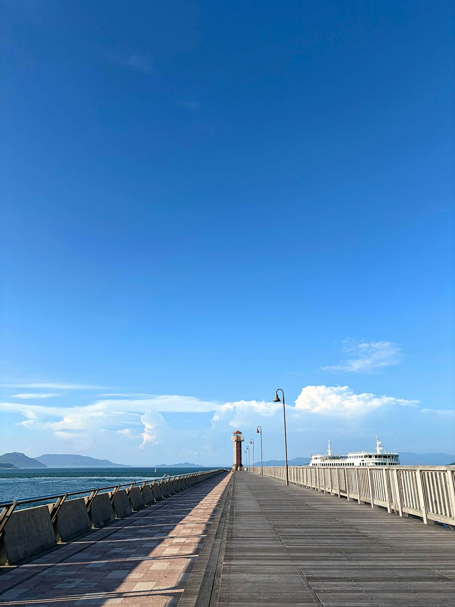 푸른 하늘 아래 바다로 뻗어 있는 부두와 등대