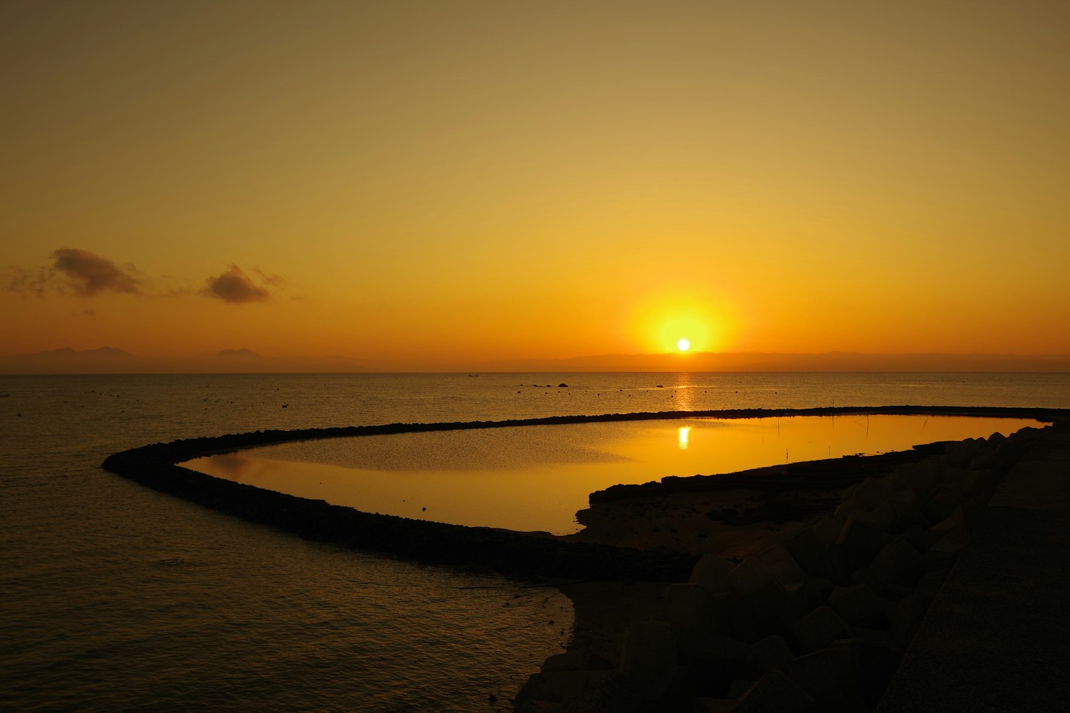 Pemandangan indah matahari terbenam di atas laut dengan siluet pantai dan breakwater