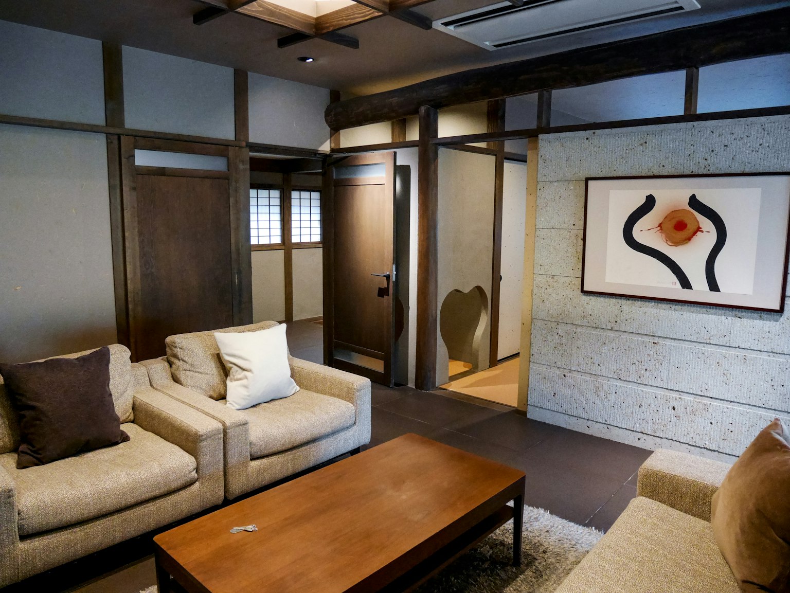 Sala de estar de estilo japonés moderno con sofás y mesa de café con obra de arte