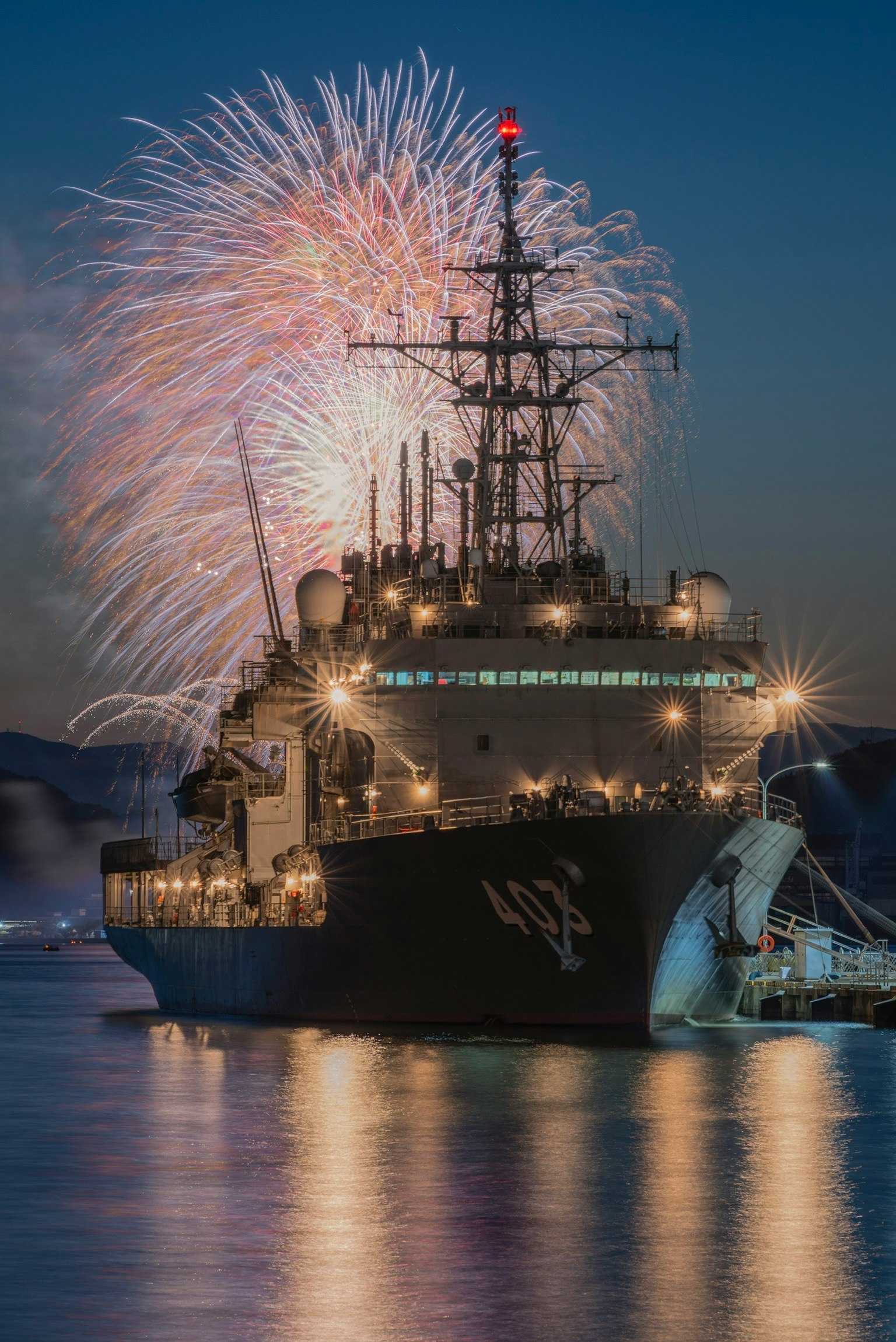 Un navire à quai avec des feux d'artifice dans le ciel nocturne derrière lui