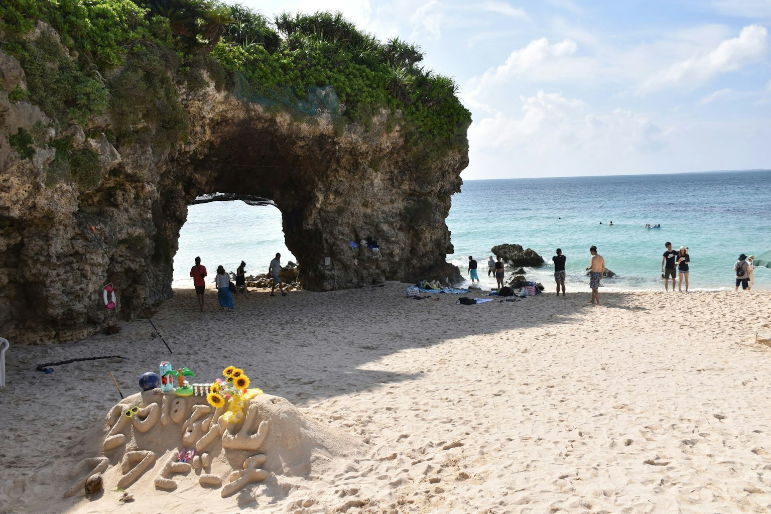 Coastal arch rock formation with people on the sandy beach