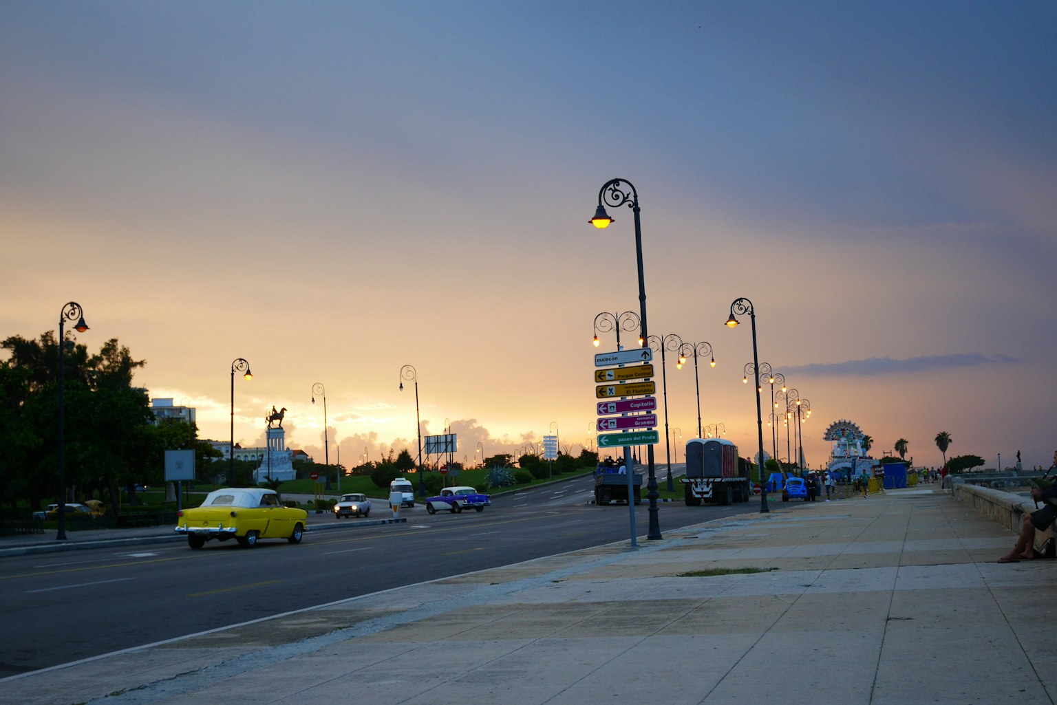 Straßenansicht mit Sonnenuntergang und Straßenlaternen gelbes Auto fährt