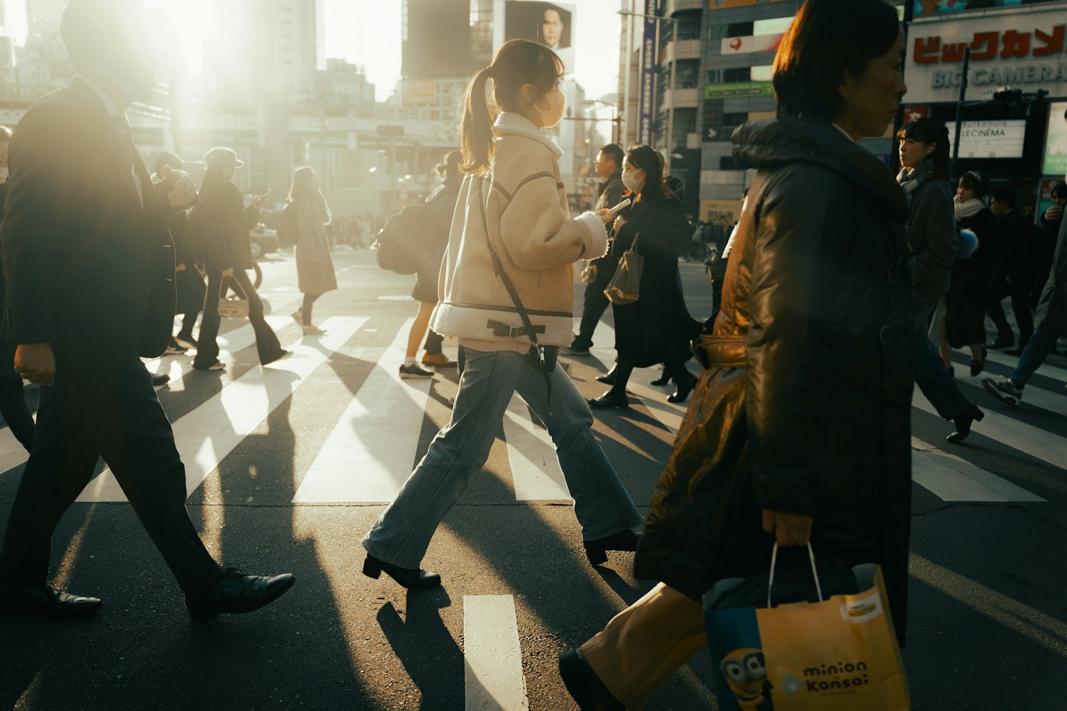 Crowd of people crossing a busy street with backlighting
