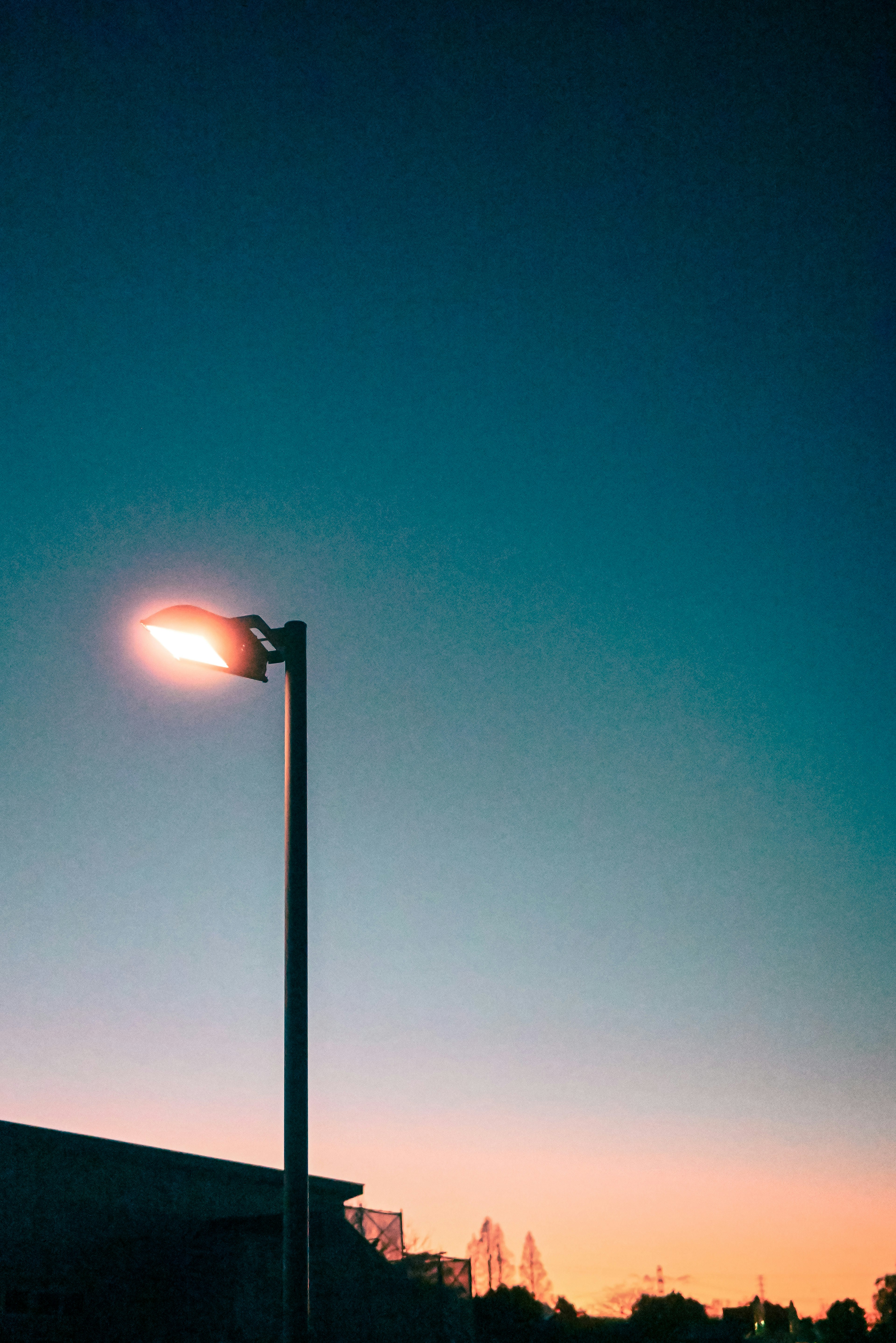 lampadaire contre un ciel de coucher de soleil avec des arbres en silhouette