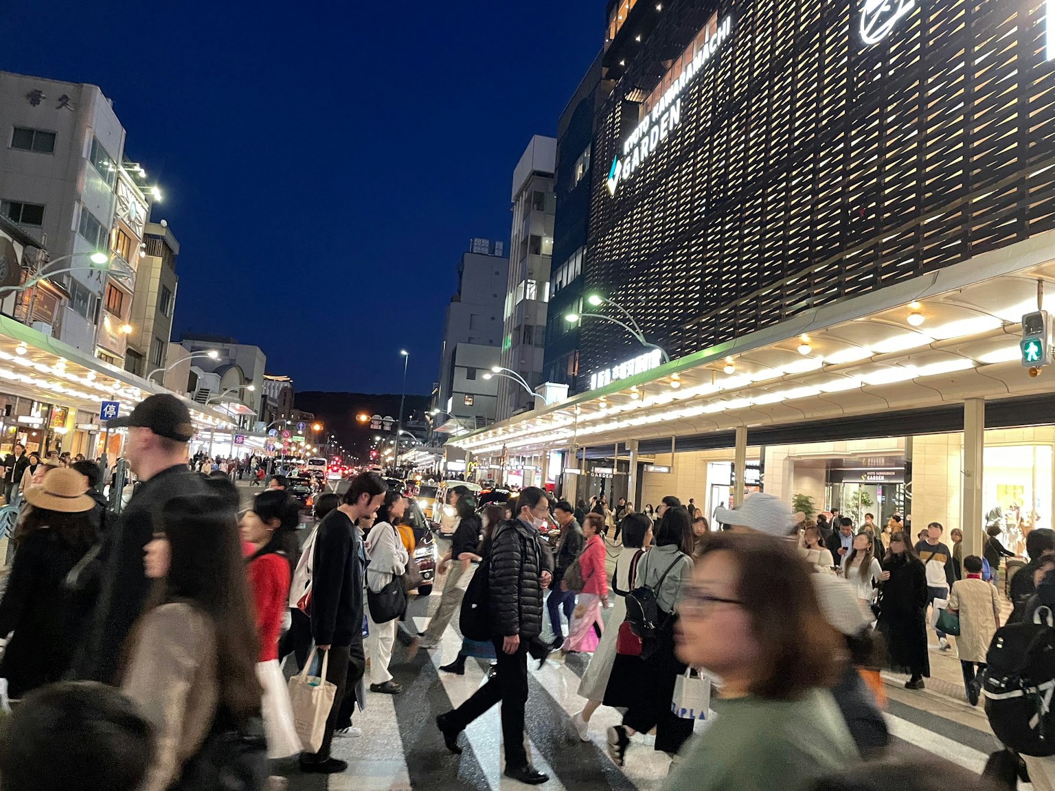 Calle comercial concurrida de noche con gente caminando